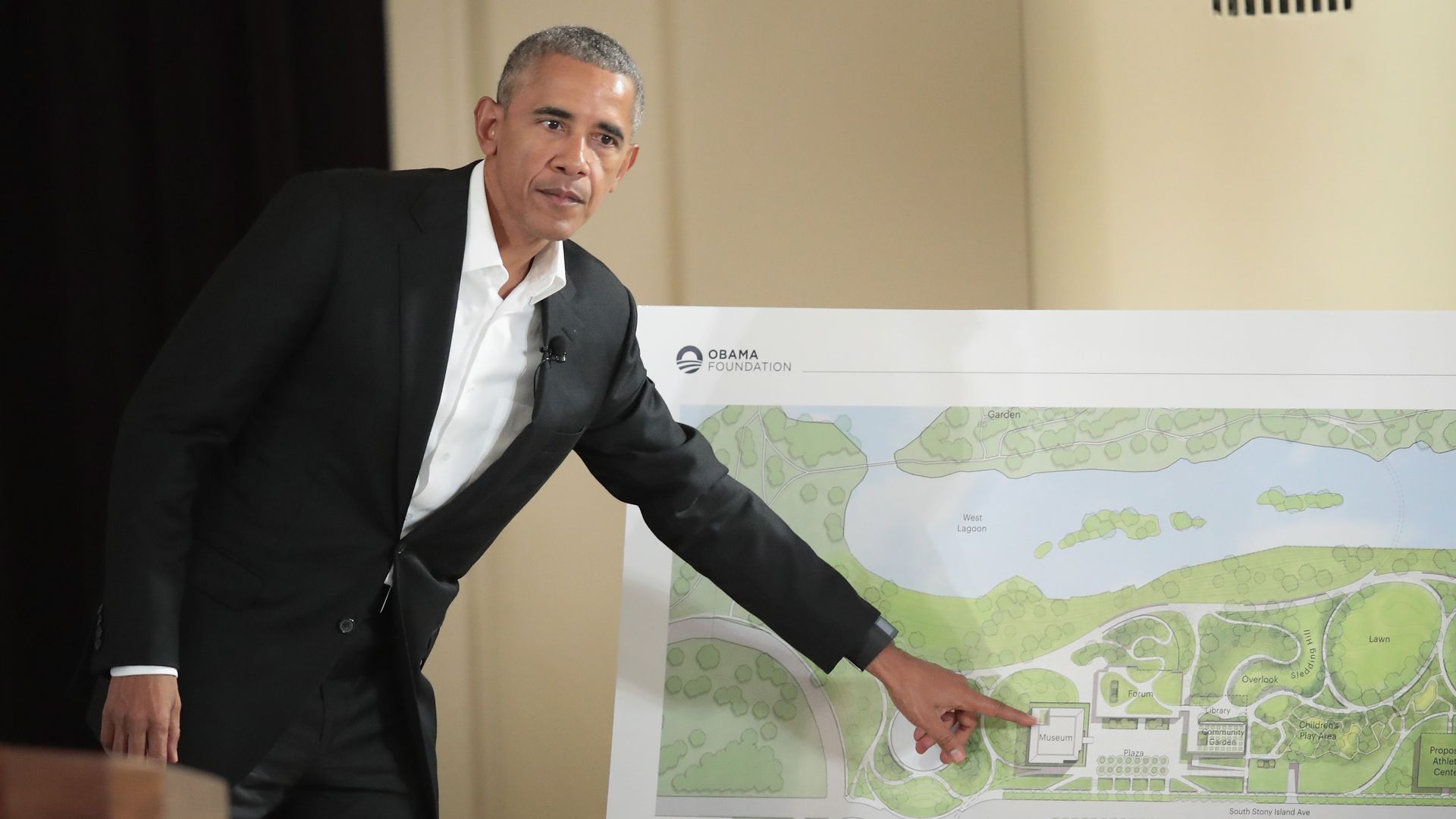 Photo of a man pointing at a map during a presentation. 