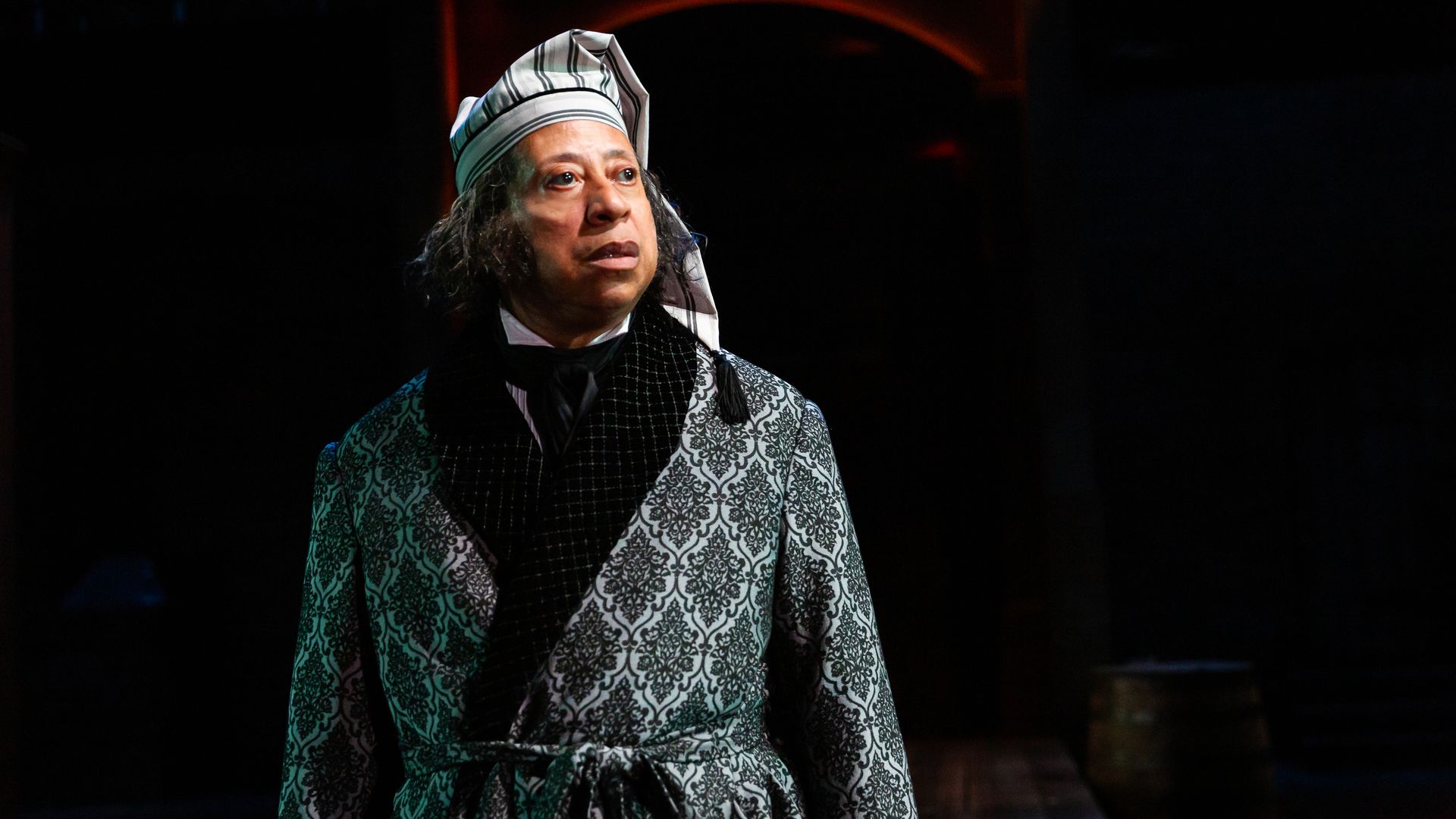 A man playing Ebenezer Scrooge stares off stage