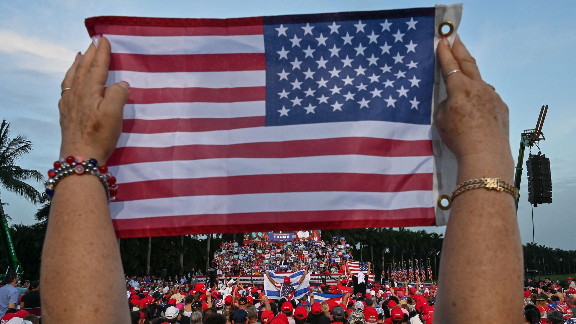 TOPSHOT - A person holds up a US flag as former US President and Republican presidential candidate Donald Trump speaks during a rally in Doral, Florida, on July 9, 2024. (Photo by GIORGIO VIERA / AFP) (Photo by GIORGIO VIERA/AFP via Getty Images)