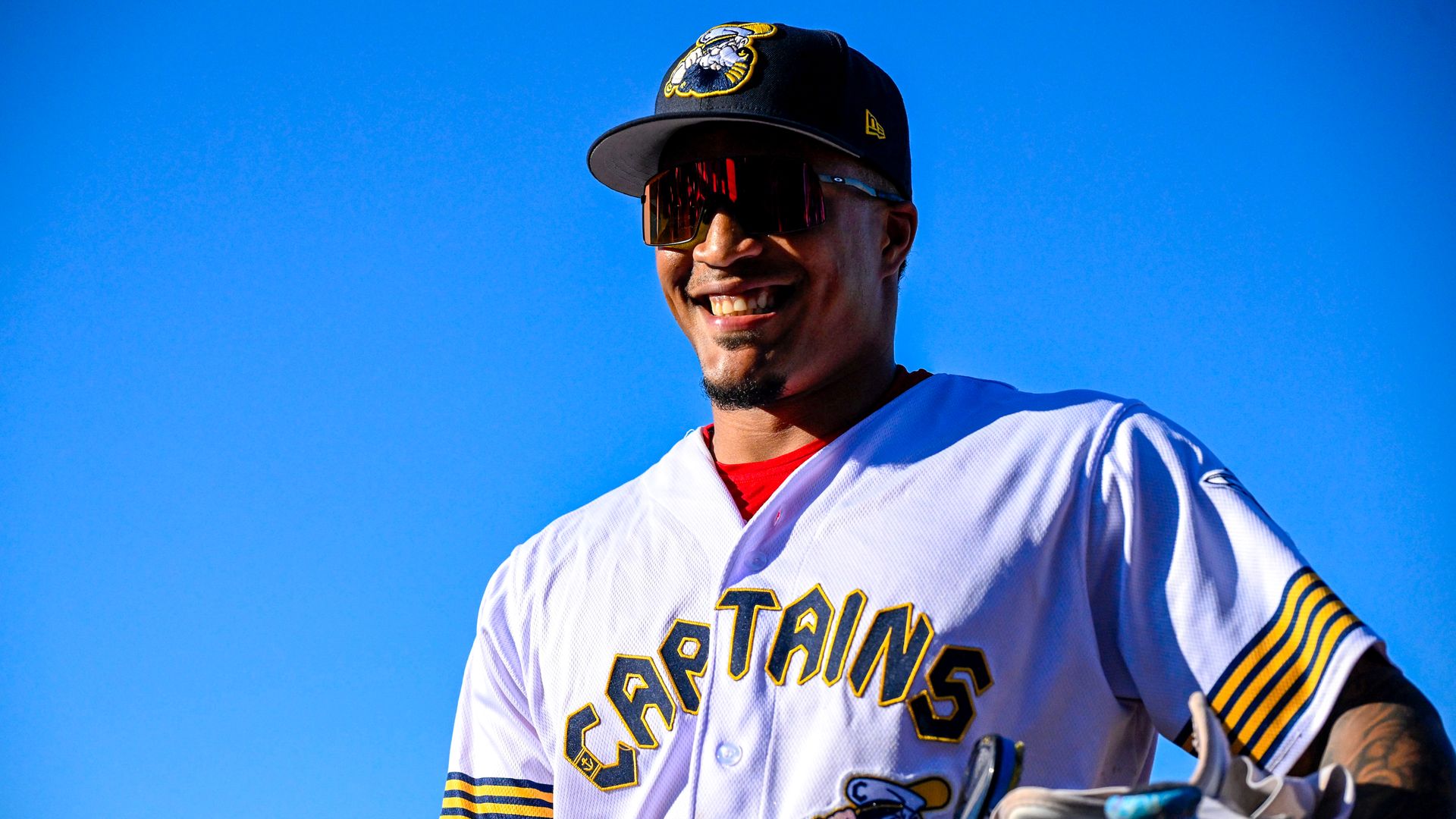 Alfonsin Rosario #27 of the Lake County Captains smiles while walking to the dugout. Blue sky.. White jersey with blue lettering.