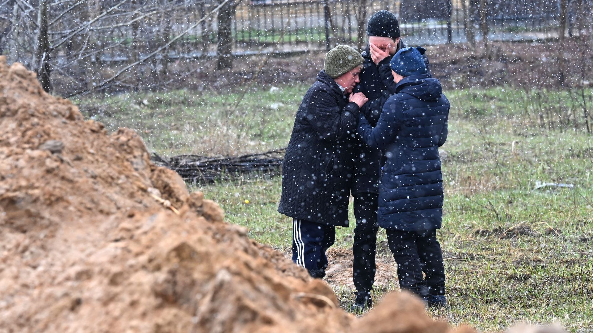 People react as they gather close to a mass grave in the town of Bucha, just northwest of the Ukrainian capital Kyiv on April 3.