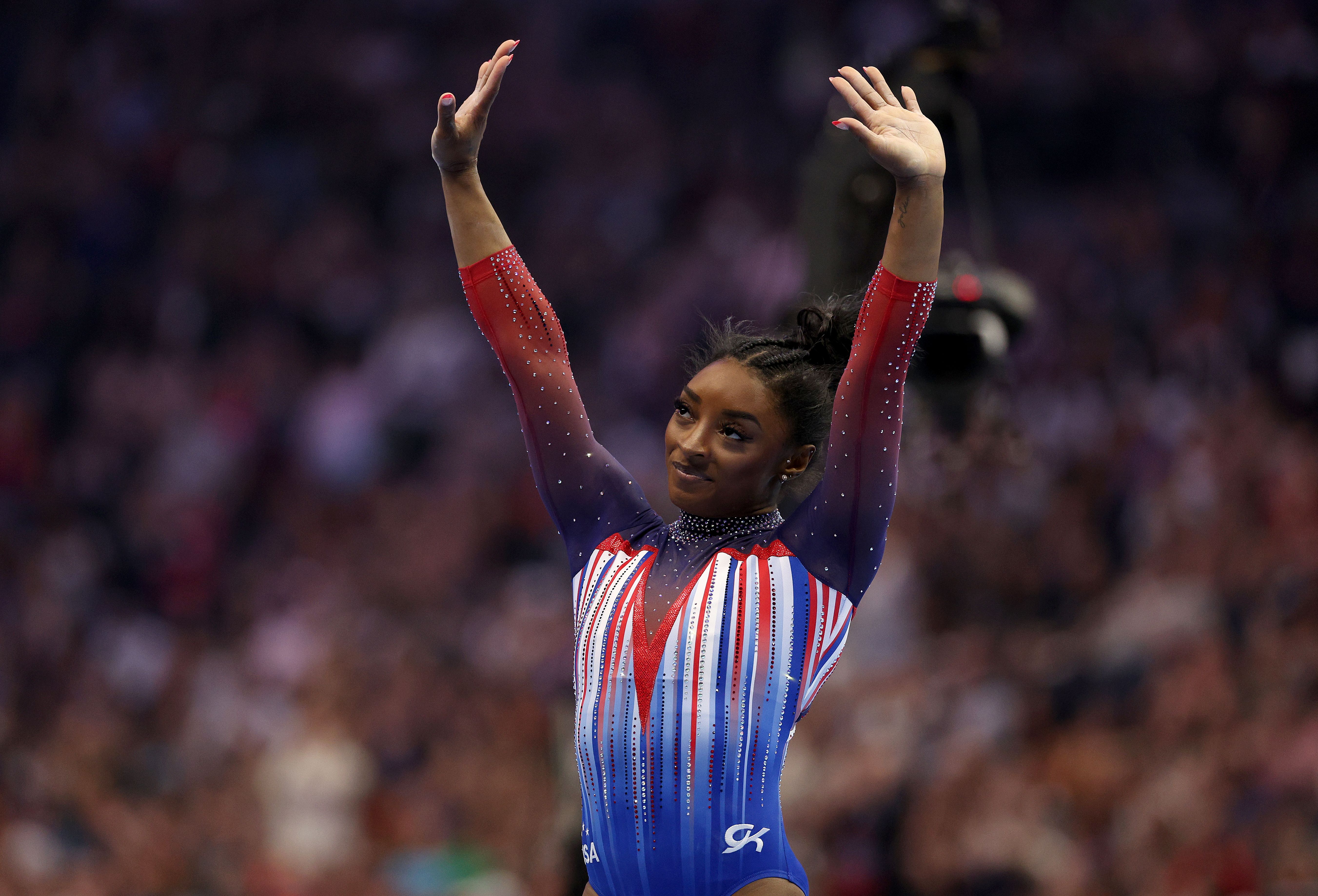 Simone Biles holds her hands in the air