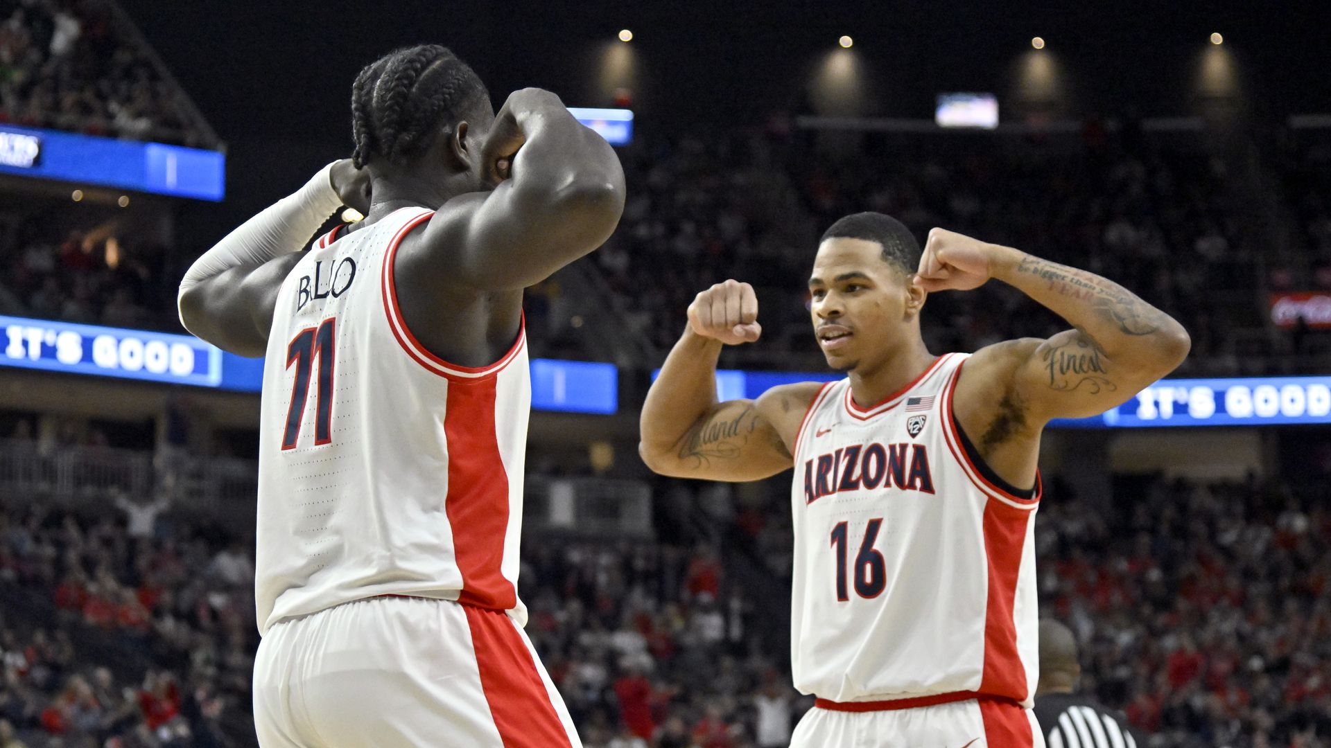 Two basketball players face each other and flex their arms.