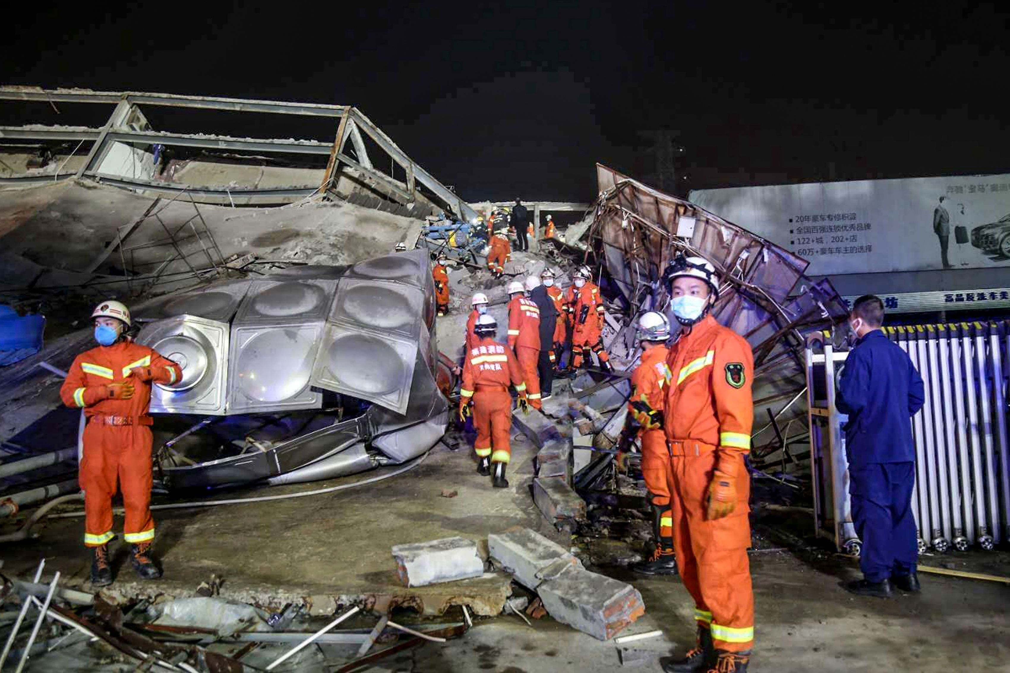 In this image, emergency workers stand in the rubble