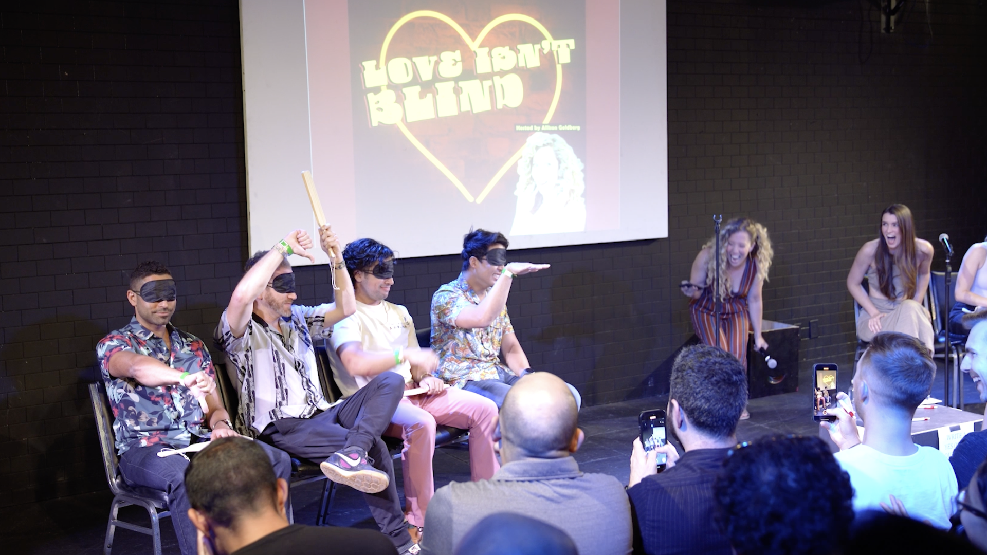 Four men in blindfolds compete for a date on the comedy show Love Isn't Blind. 