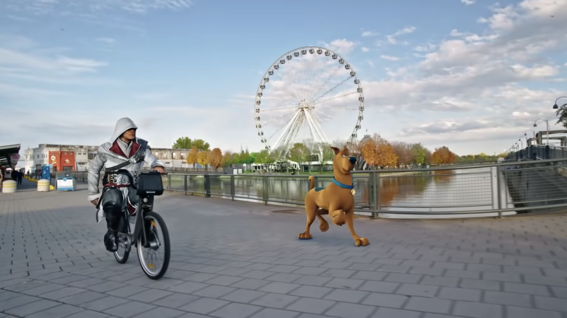 Screenshot of a video of a costumed man on  a bicycle and a brown cartoon dog, with a ferris wheel in the background