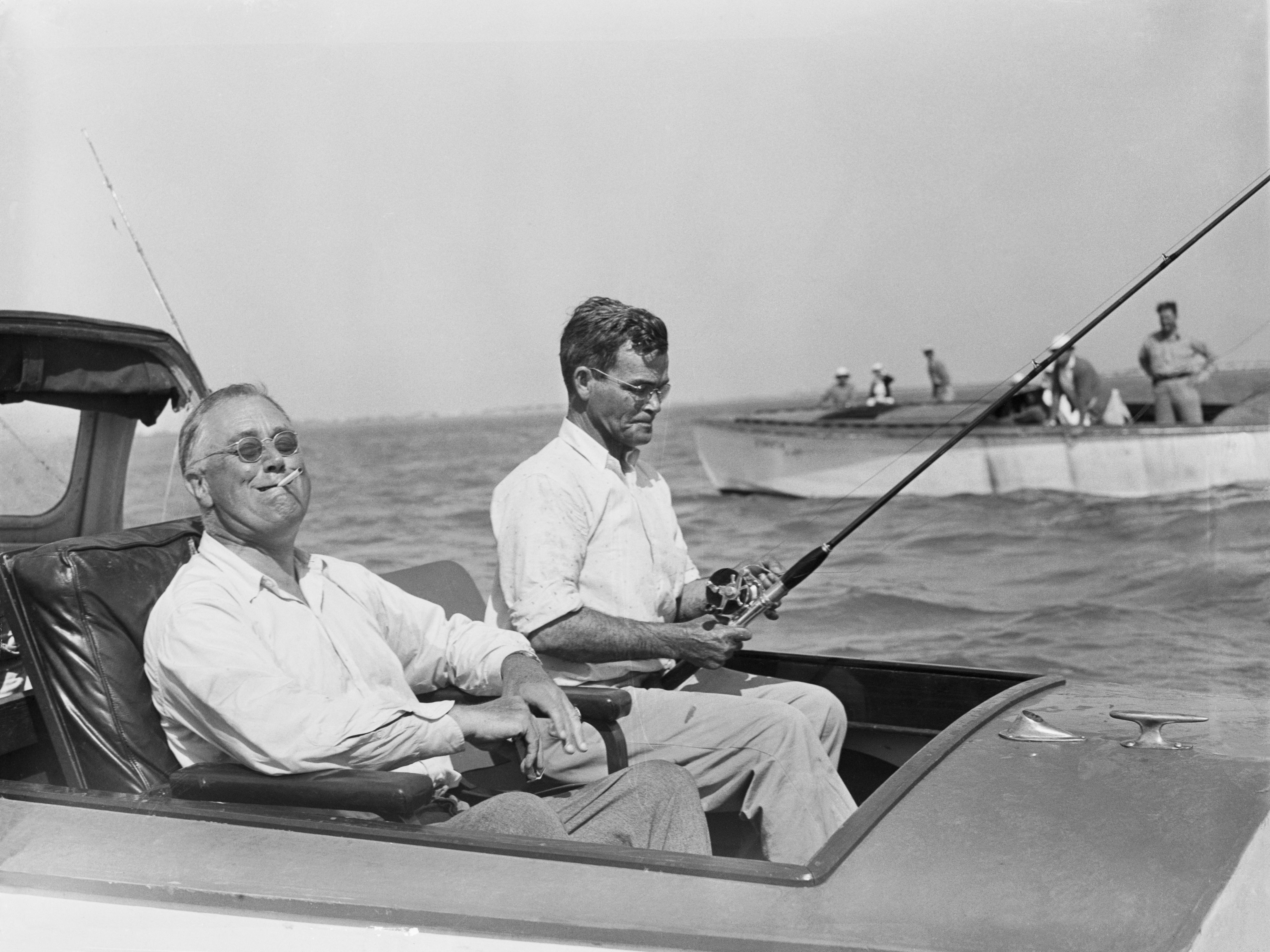 President Roosevelt puffs a cigarette here, while fishing for tarpon during his vacation on the Gulf of Mexico.