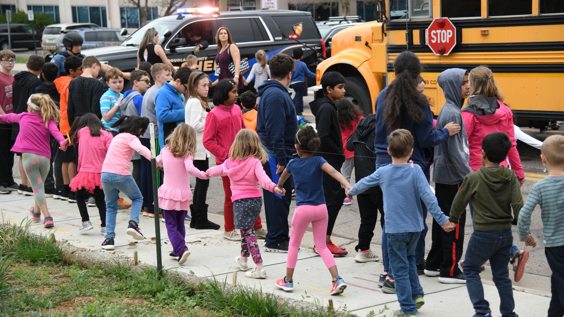 Students escorted school bus in front of STEM School Highlands Ranch after a shooting. 