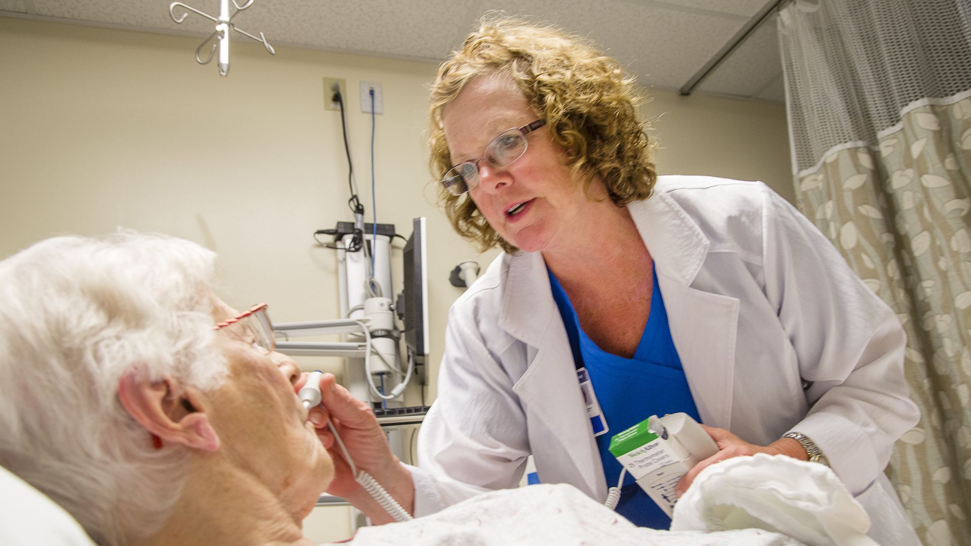 An ER nurse takes the temperature of a patient.