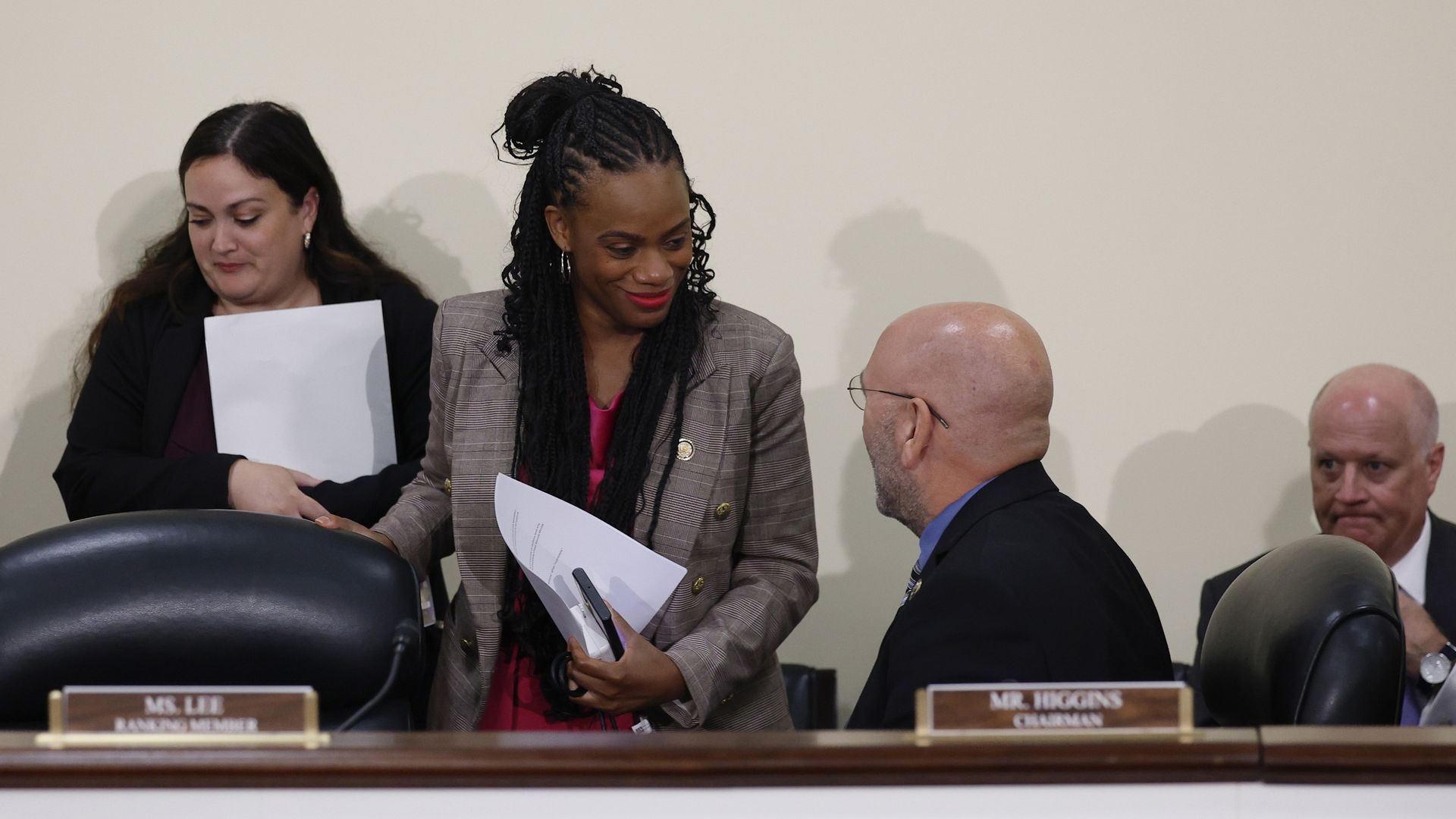Subcommittee Chair Rep. Clay Higgins sits as he speaks with Ranking Member Rep. Summer Lee, who is smiling and standing while holding a piece of paper.