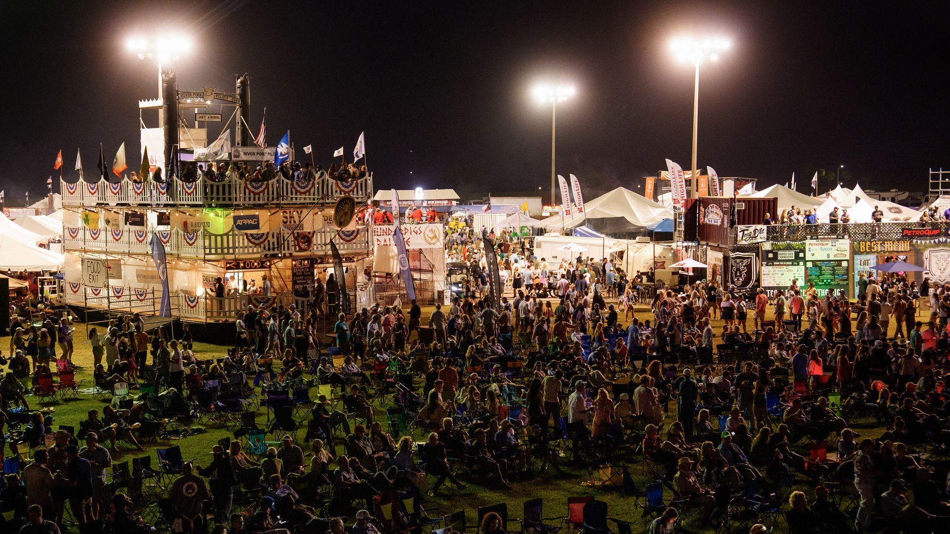 Image shows crowd with tents behind them.