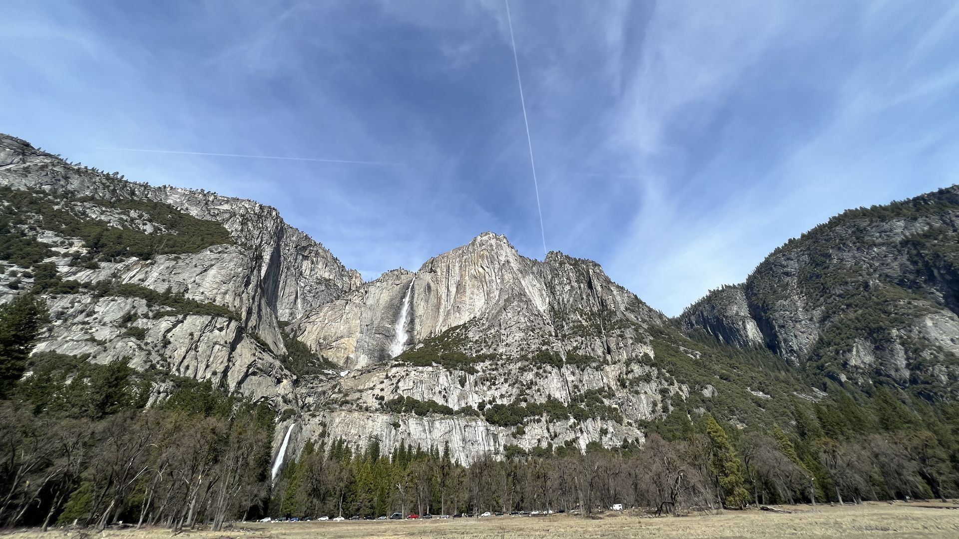 A wide image of Yosemite against a blue sky with clouds