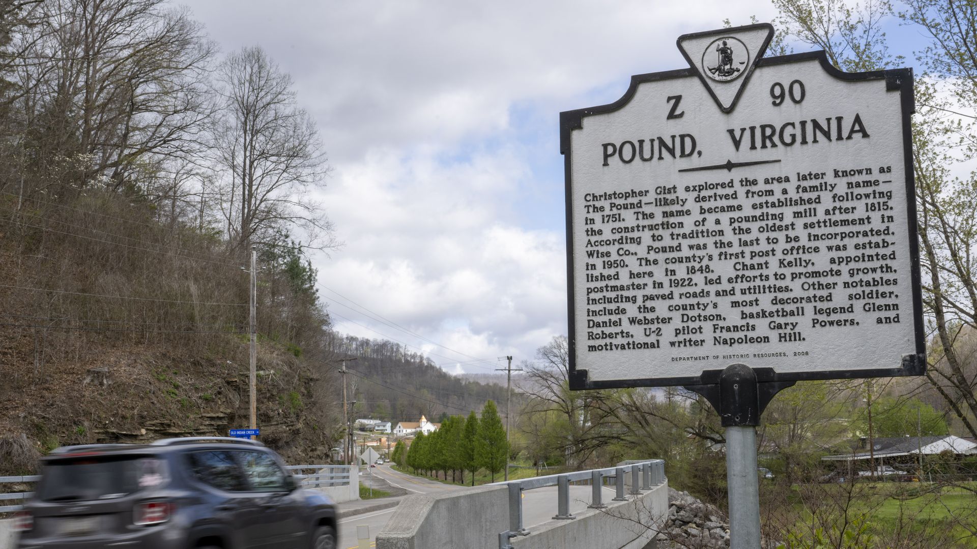 A car is shown crossing over a bridge surrounded by greenery. To the right is a sign that says "Pound, Virginia"