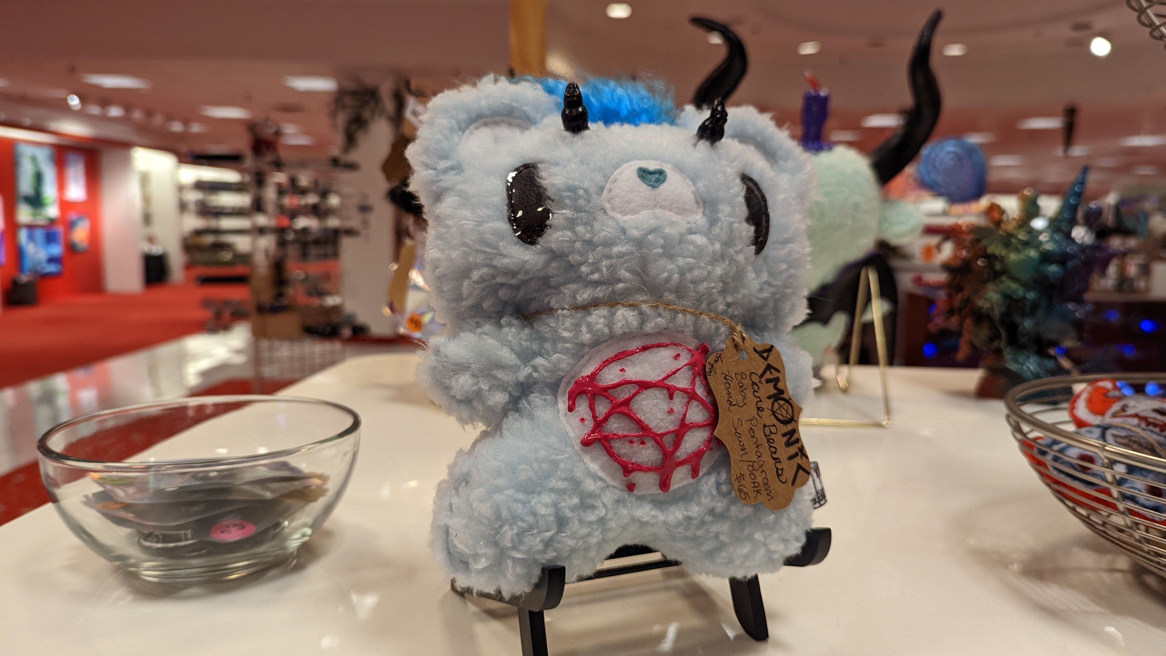 A Care Bare stuffed animal features a pentagram on its belly and horns on its head.