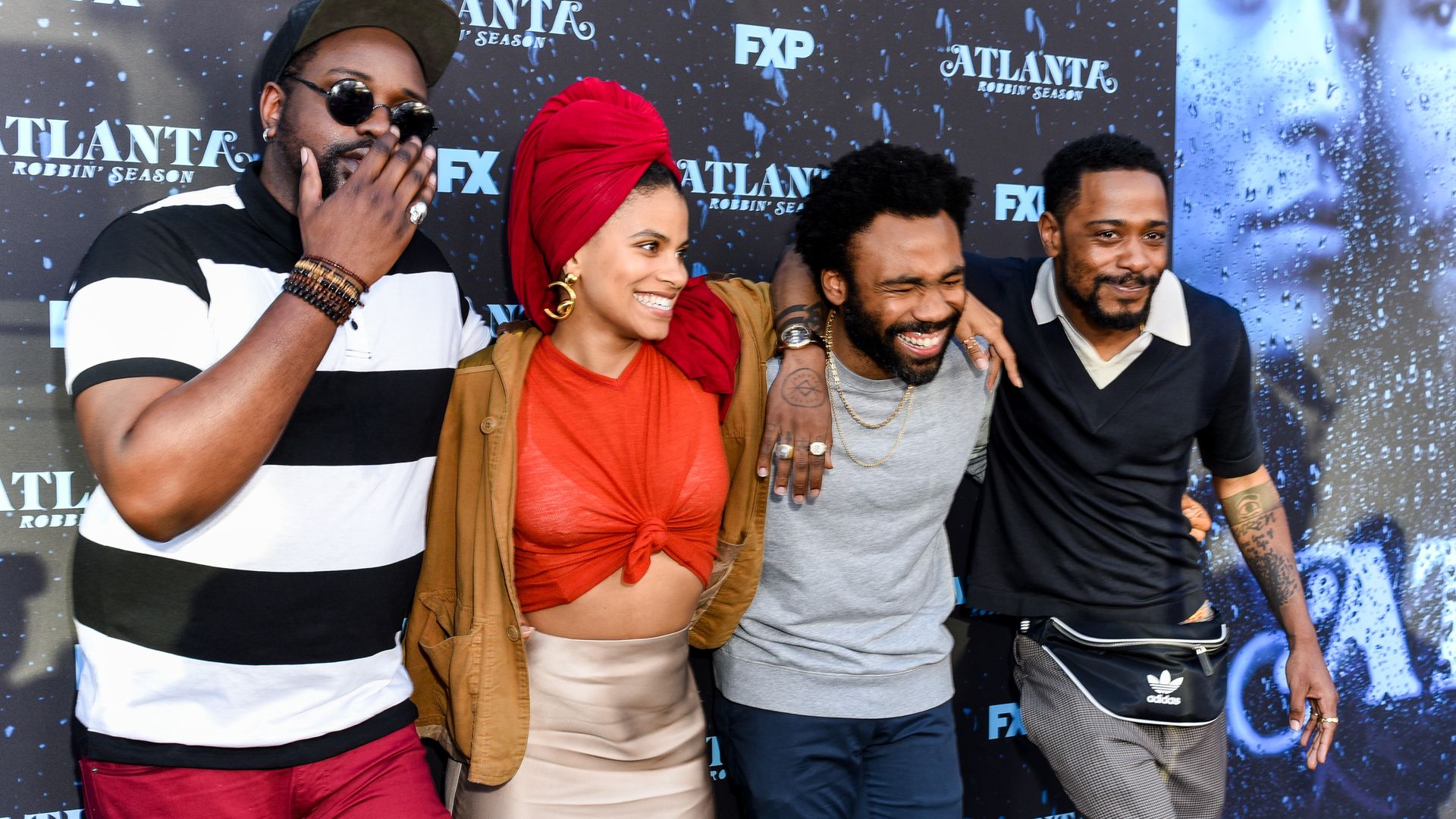 Three men and one woman smile for photographers with their arms around each other at an event for the TV show "Atlanta."
