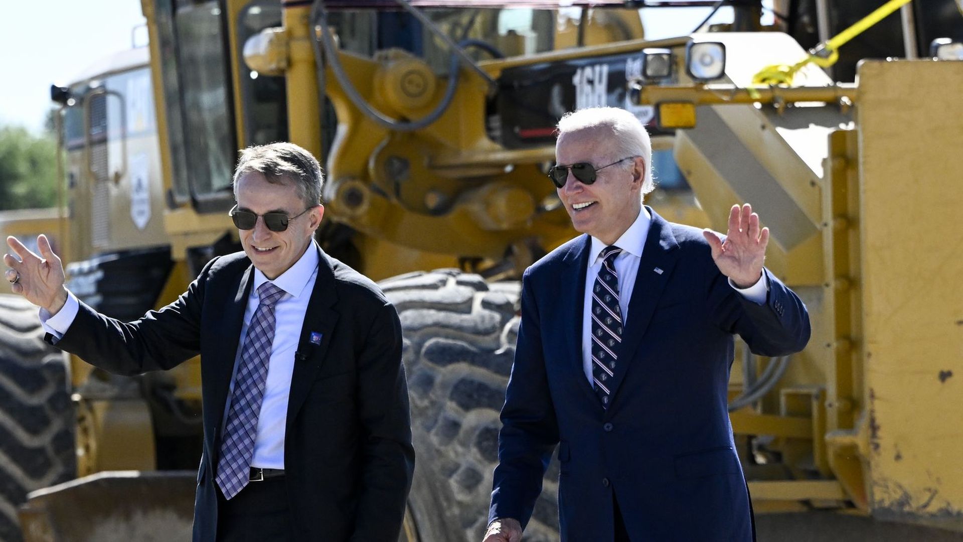 President Biden and Intel CEO Pat Gelsinger walk in front of heacy machinery at a groundbreaking ceremony.