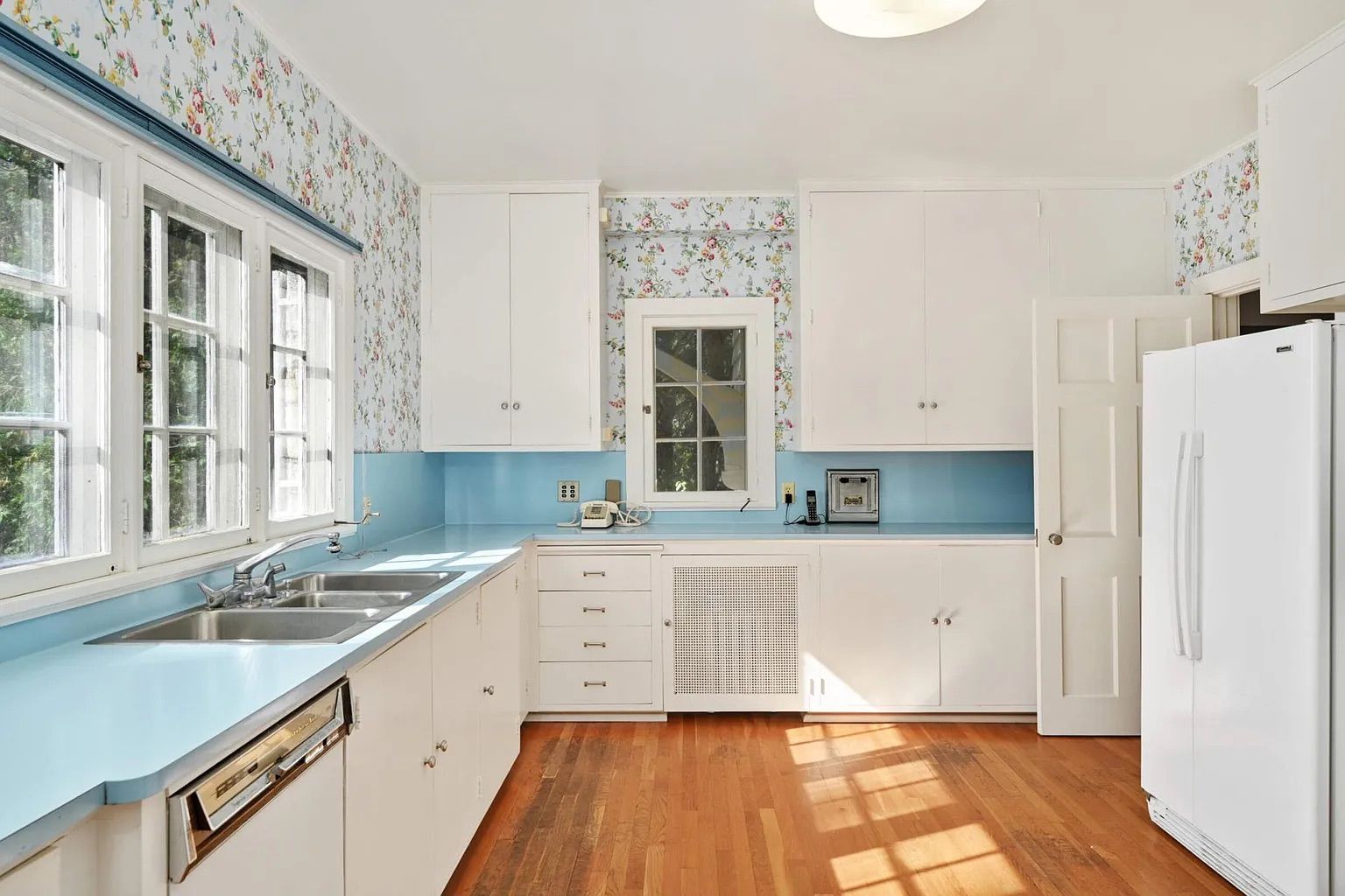 A kitchen with white cabinets and blue wallpaper.