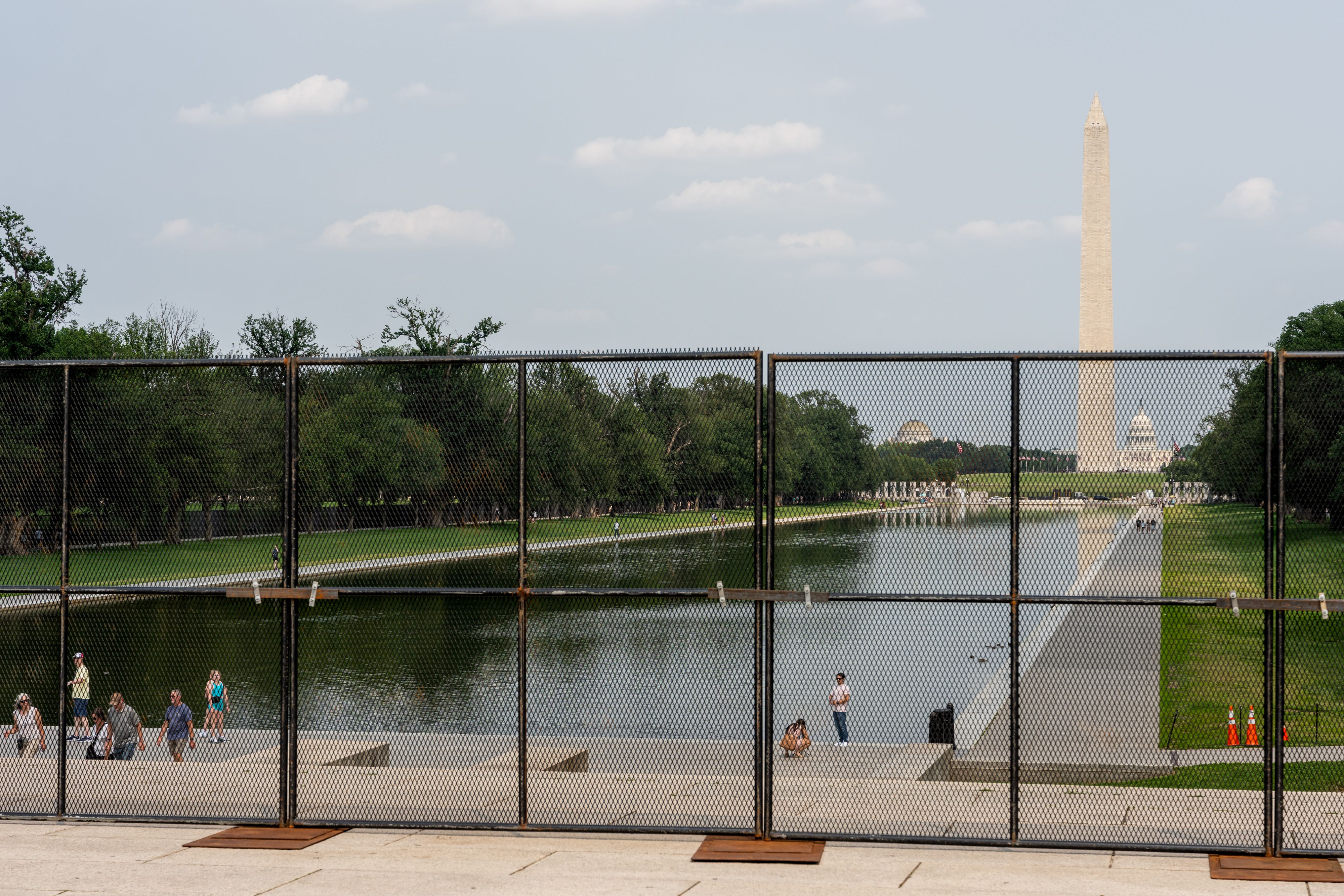 A photo of the Washington Monument and reflecting pool behind security fencing.