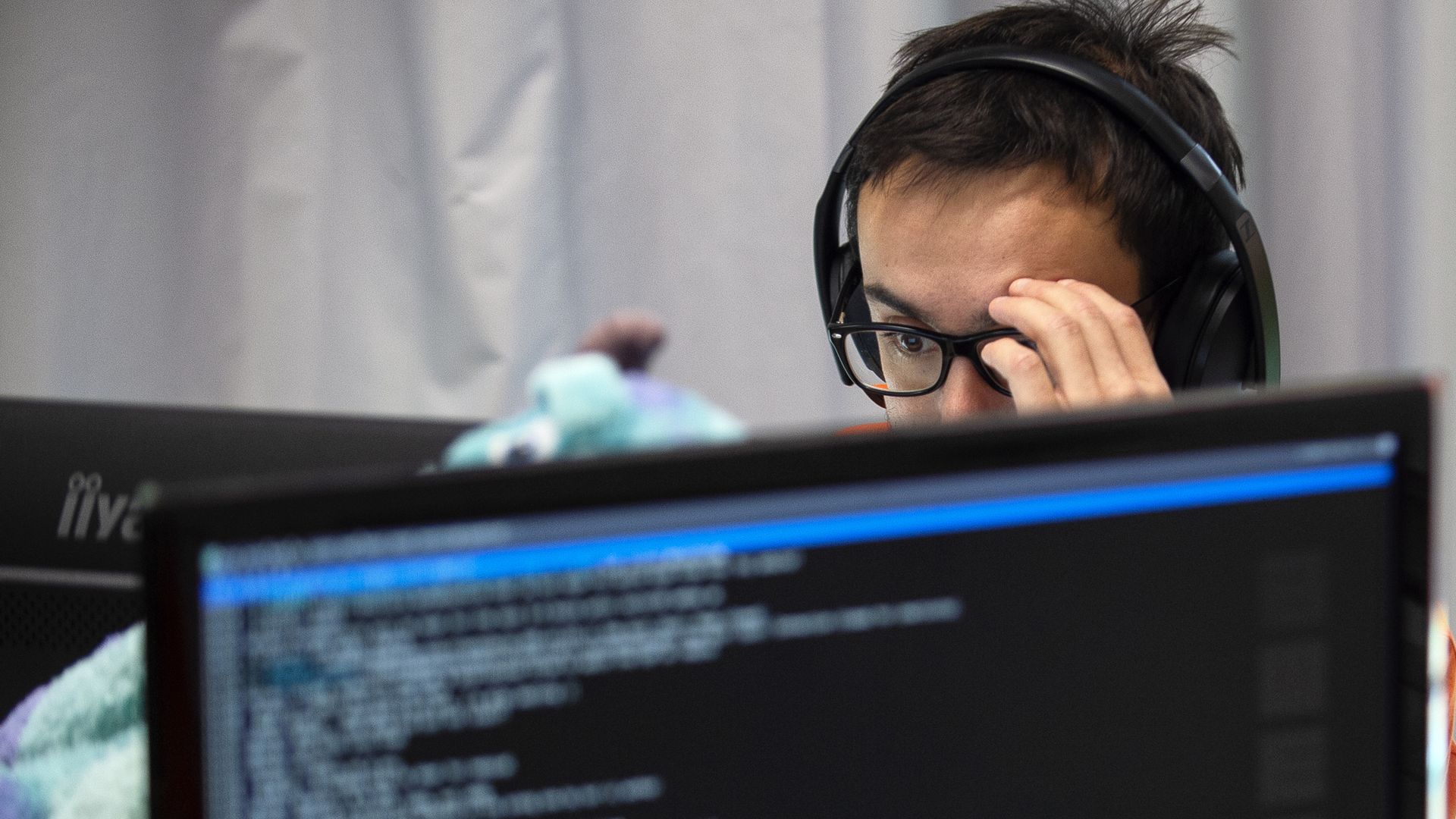 A student sits with headphones staring at a computer.