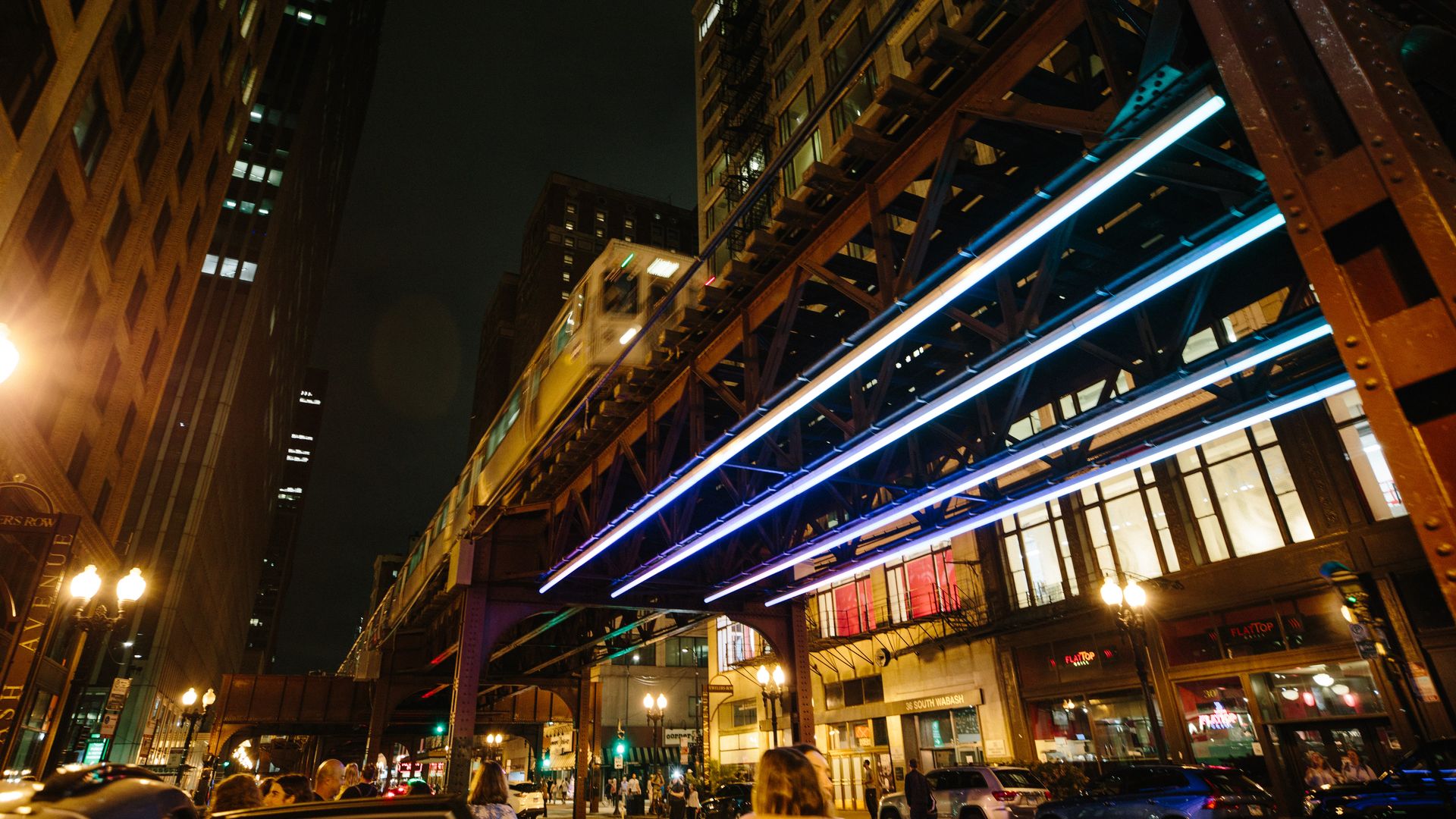 Train on elevated tracks that is lighted from below.