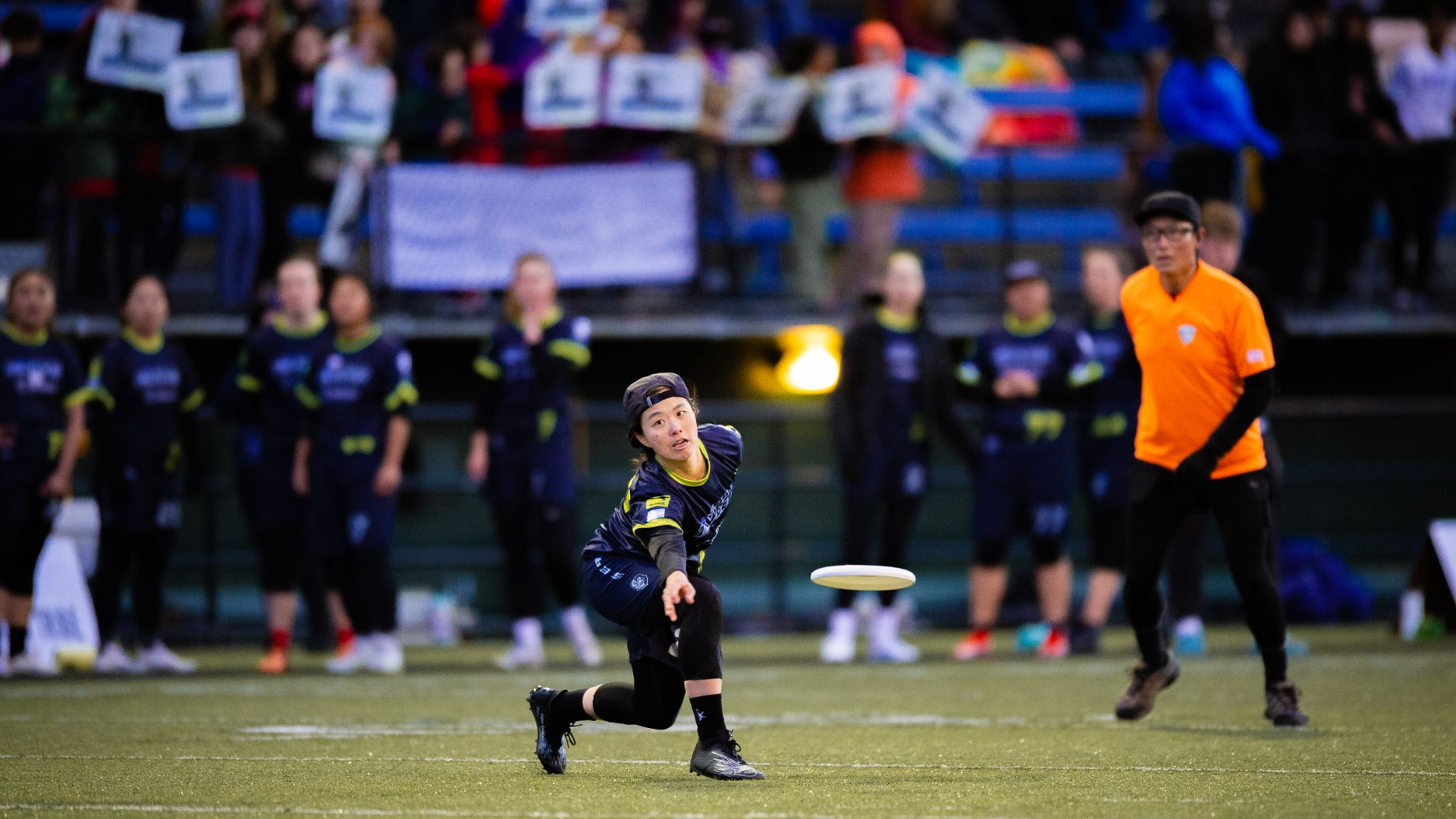 Ultimate (Frisbee) player on the field with a disc soaring through the air