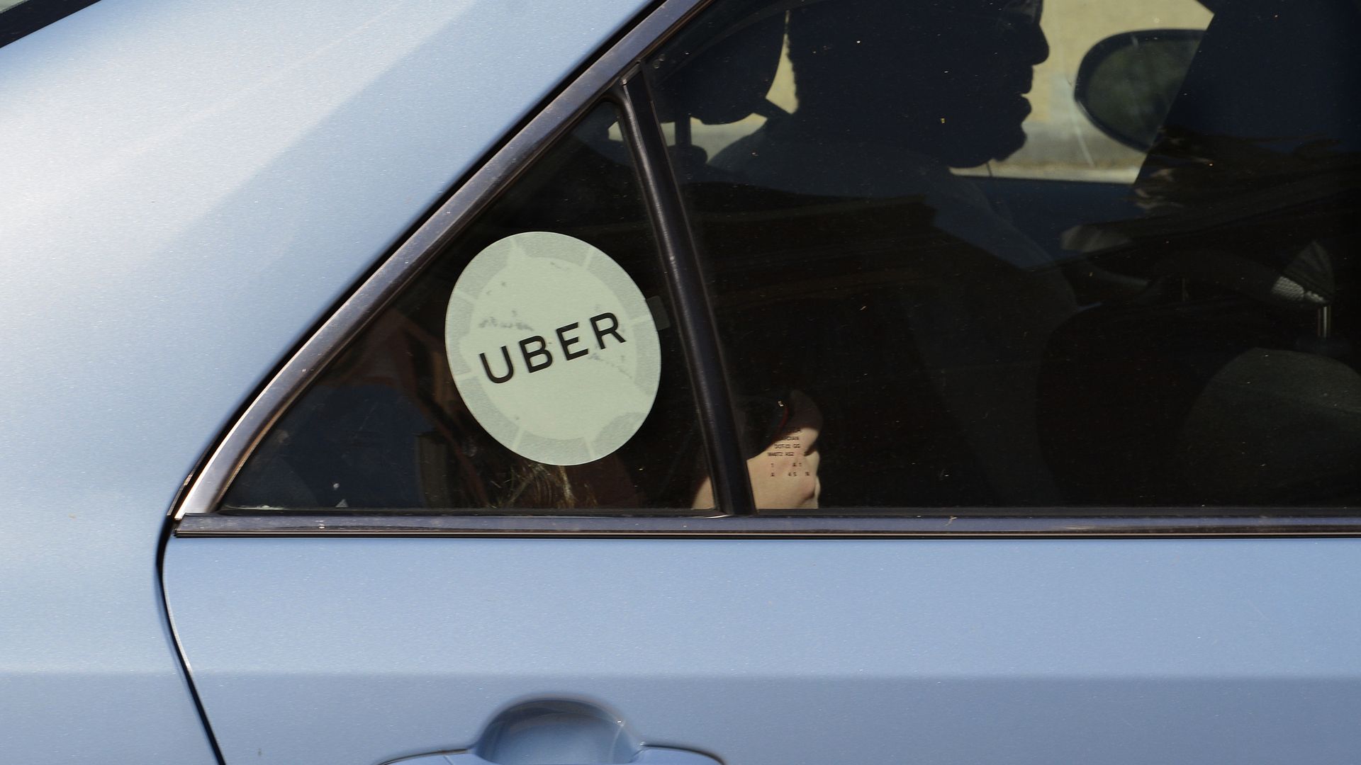 Picture of the back door of a blue car with an Uber sticker