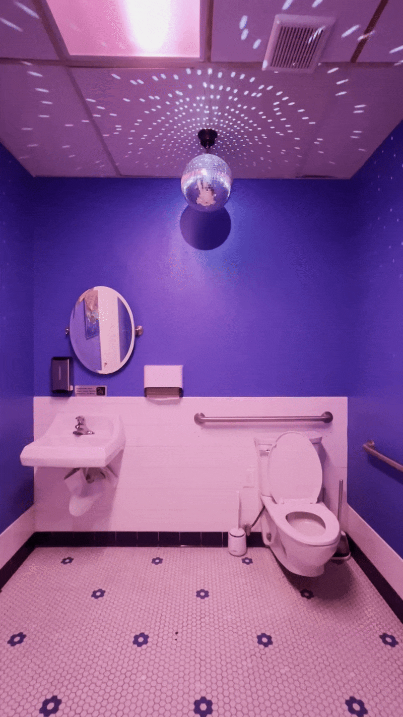 A bathroom with royal blue walls and a spinning disco ball.