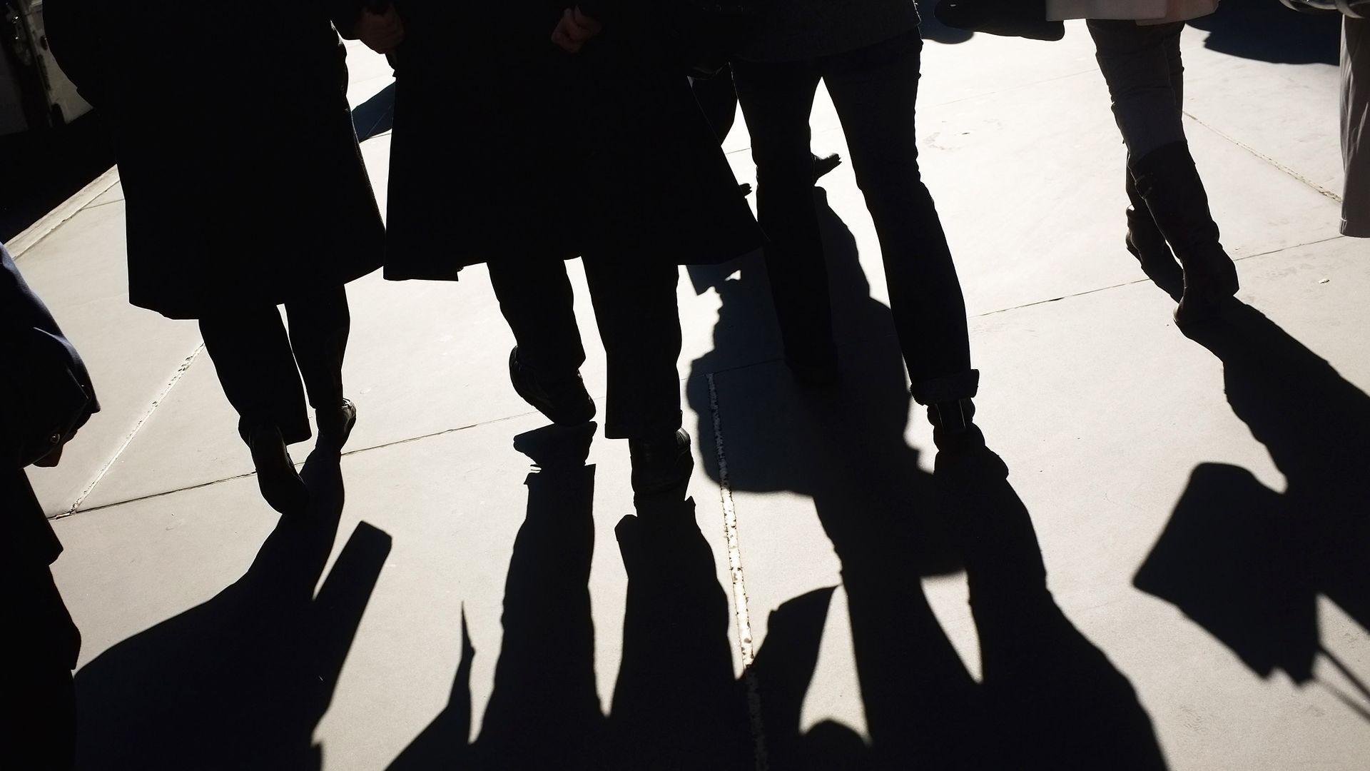 The legs of businessmen and shoppers walk along Madison Avenue