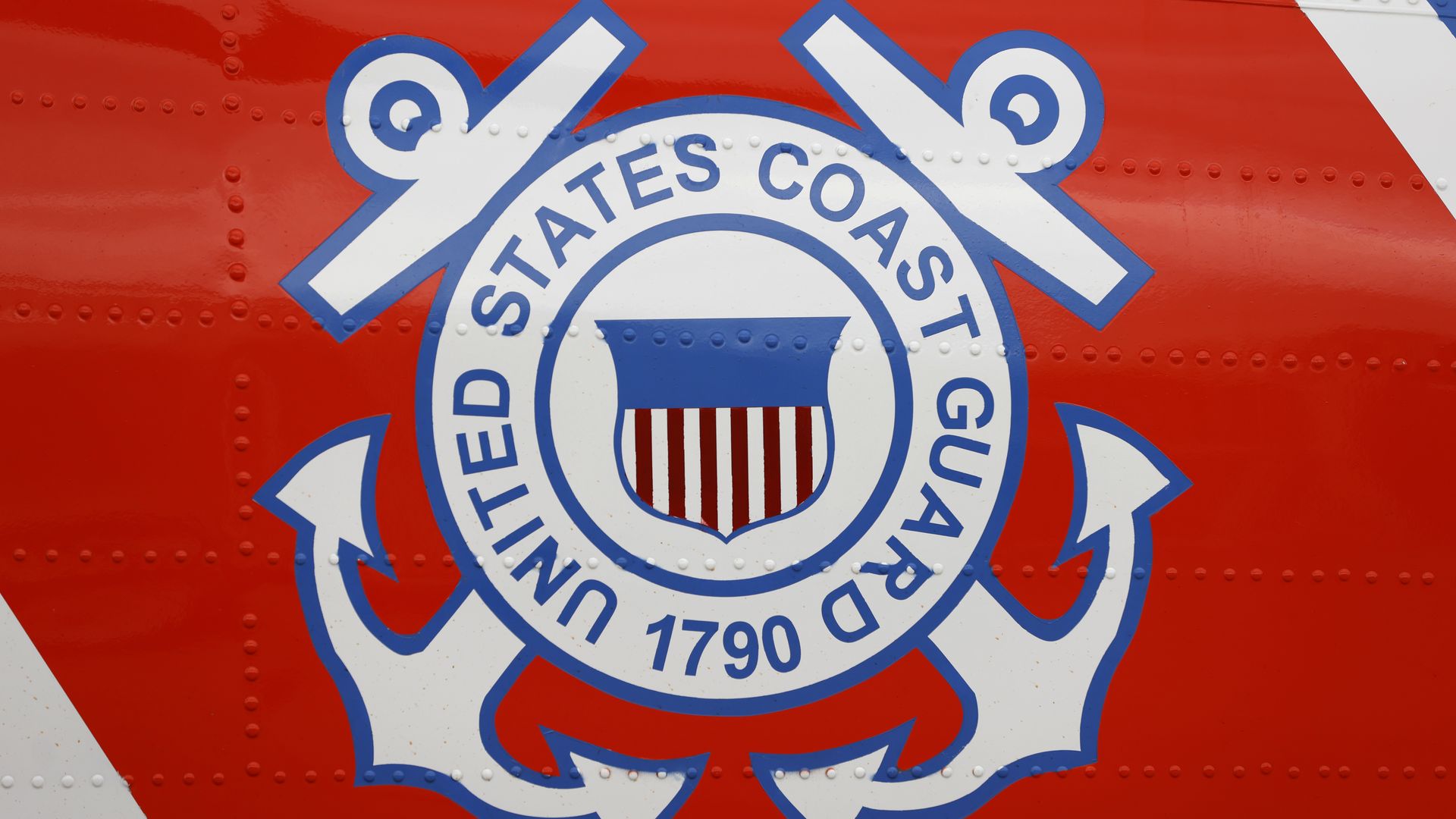 The U.S. Coast Guard logo is shown on the side of a helicopter. 