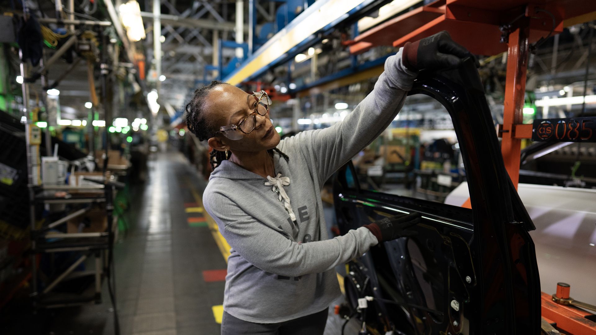 Image of a GM worker adding a door to a vehicle at GM's Fairfax Assembly plant in Kansas.