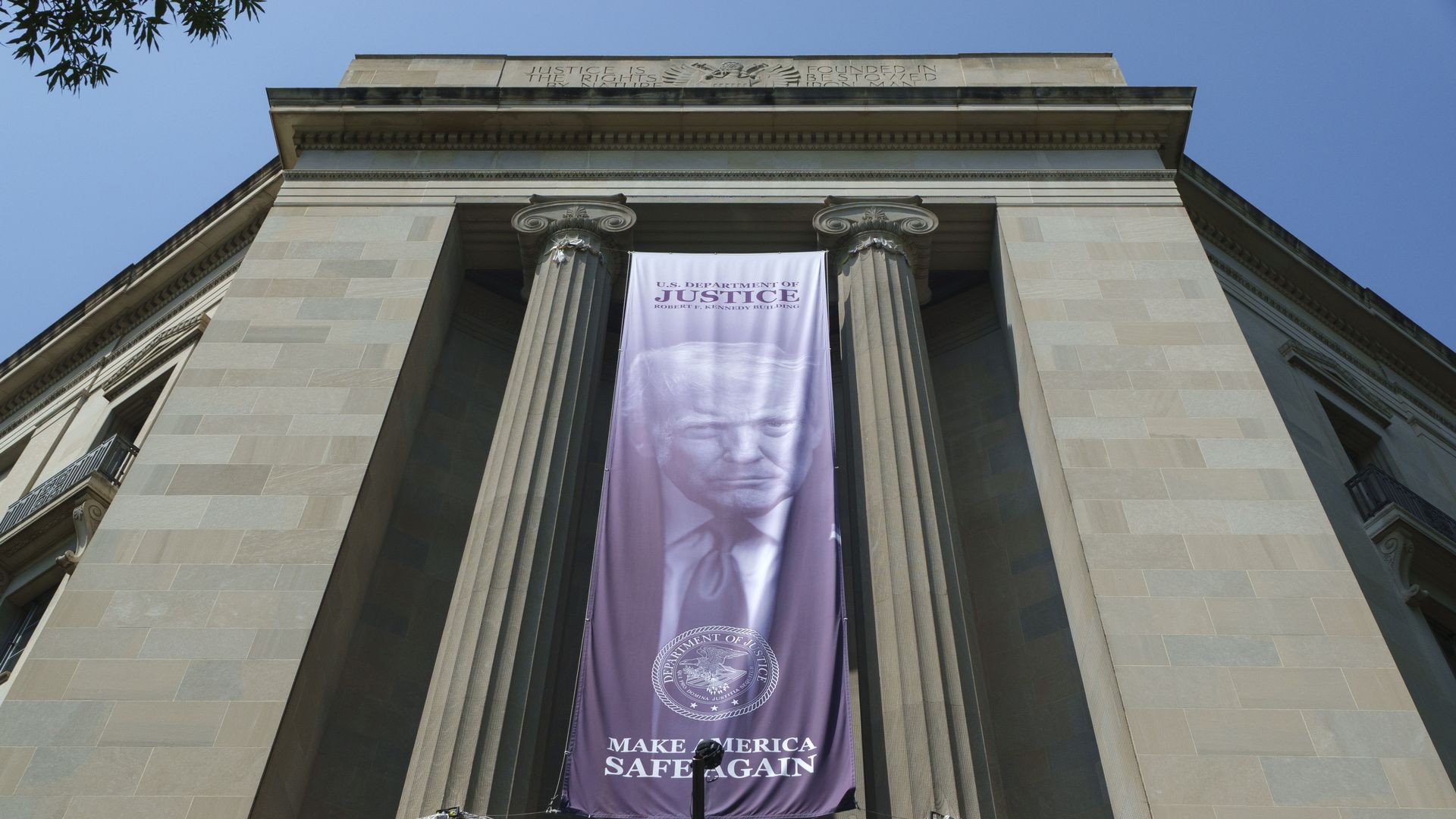A banner showing a picture of President Trump hangs from a building between two columns with the words "MAKE AMERICA SAFE AGAIN."
