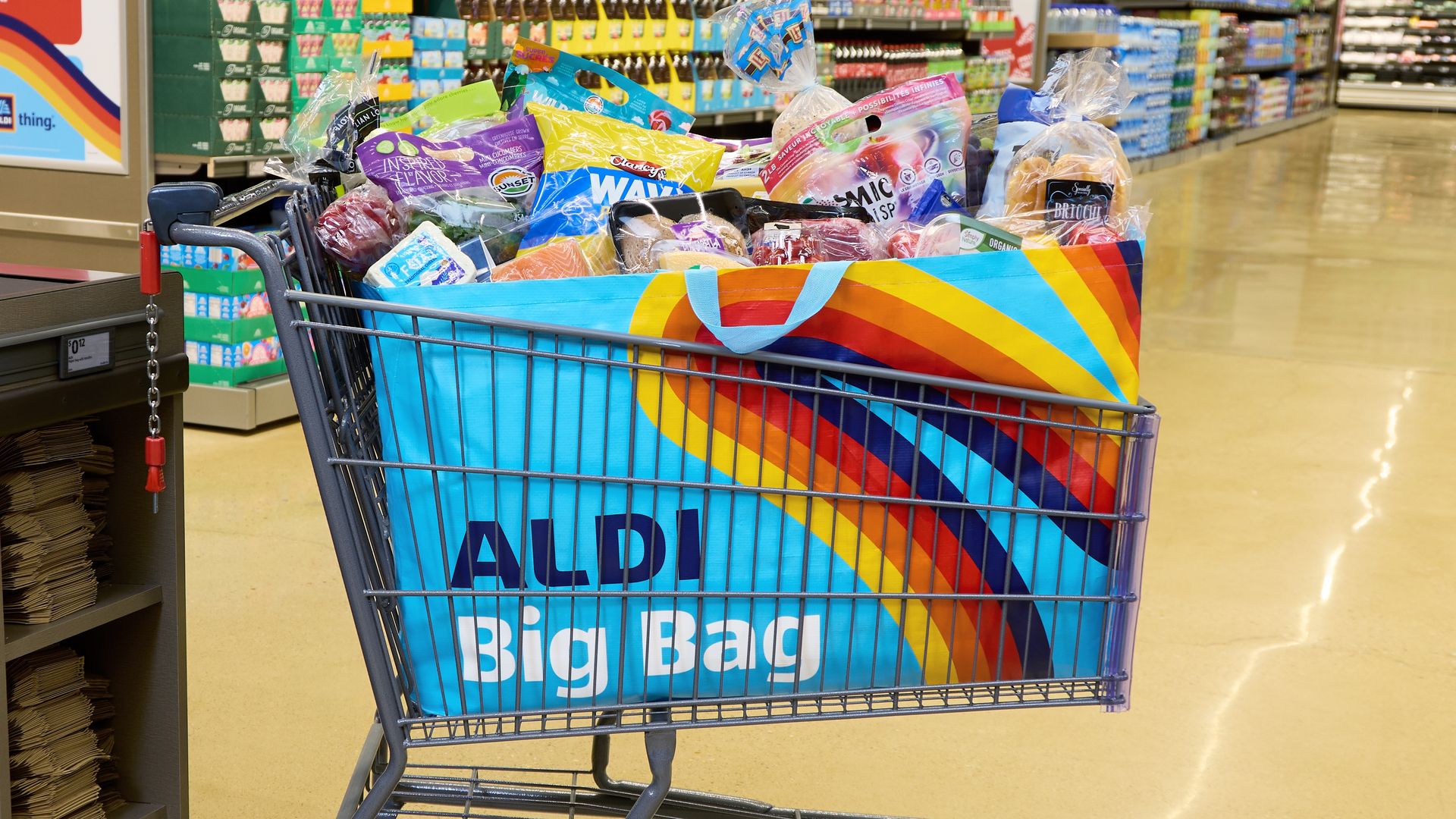 Shopping cart with a massive blue shopping bag labeled "ALDI Big Bag" filled with groceries.