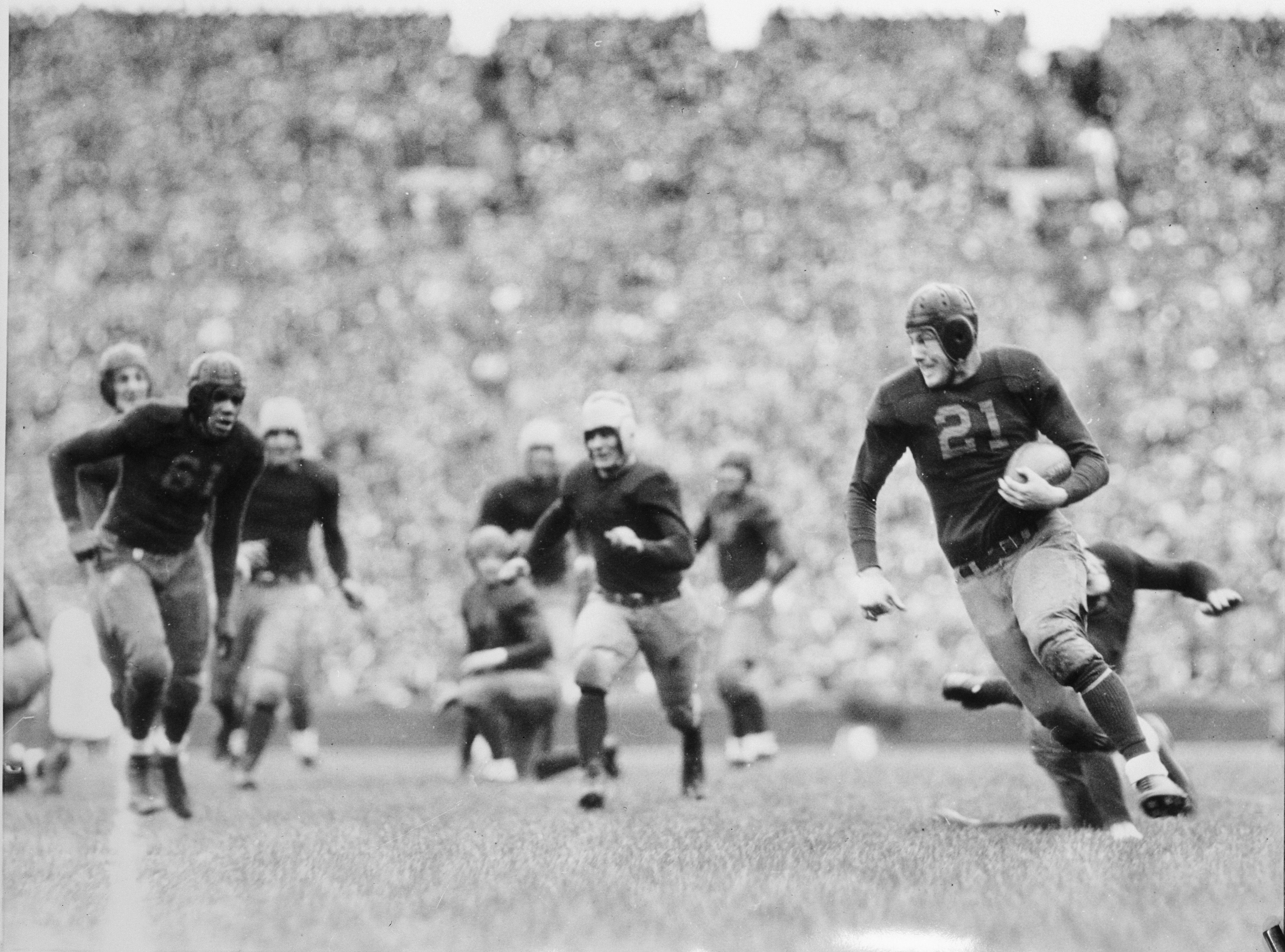 Michigan football player John Heston runs with the ball as others look on.