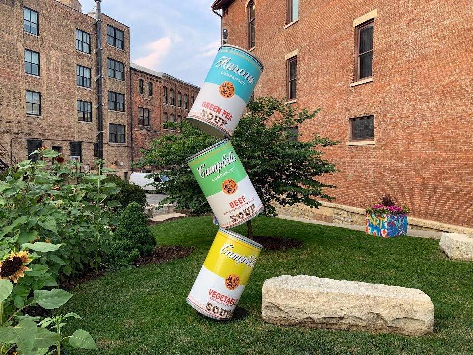 Massive stacked Campbell's soup cans from Andy Warhol stand in a park in Aurora.