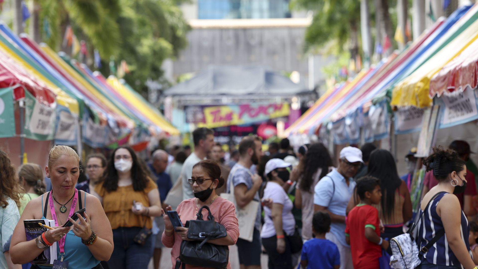 Groups of people walk outside at the Miami Book Fair.