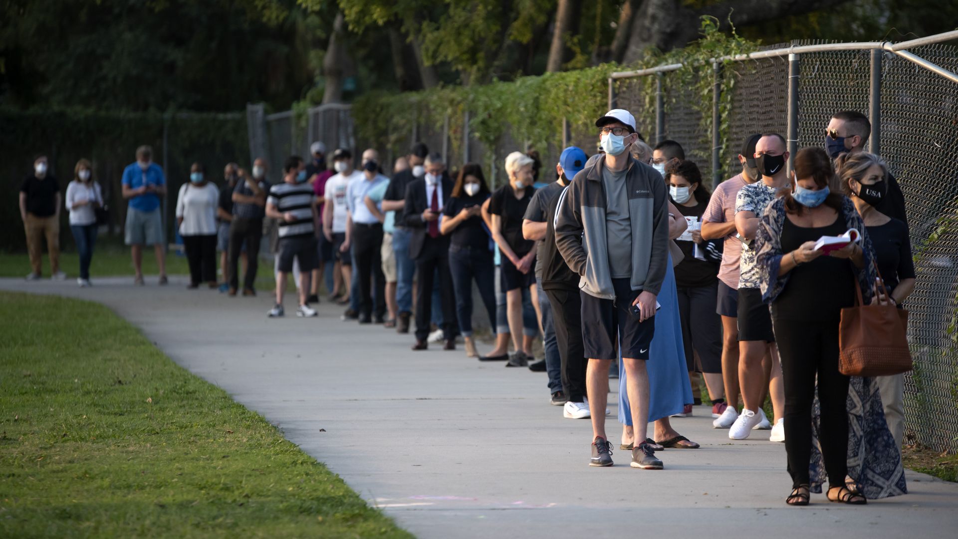 A line of voters stand on a sidewalk