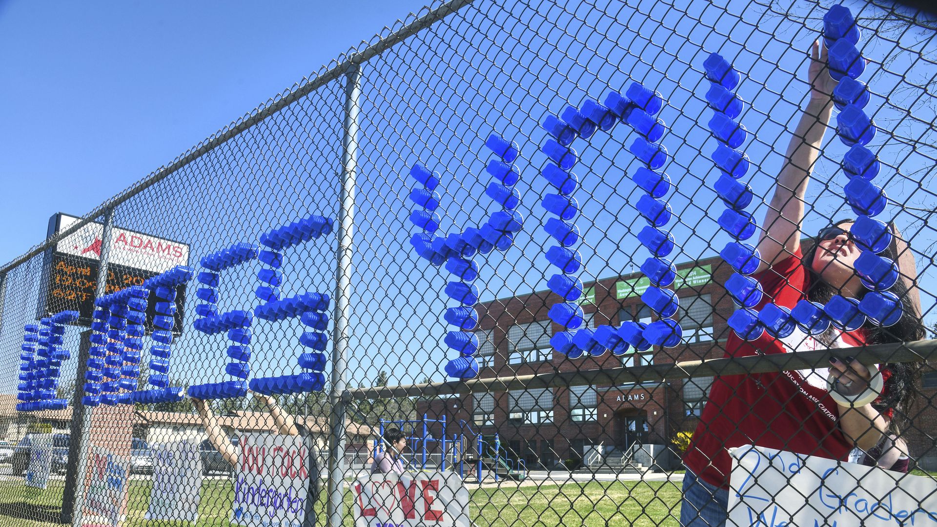 In Spokane, Elementary School teachers use plastic cups to build a "We Miss You All-Stars" message.