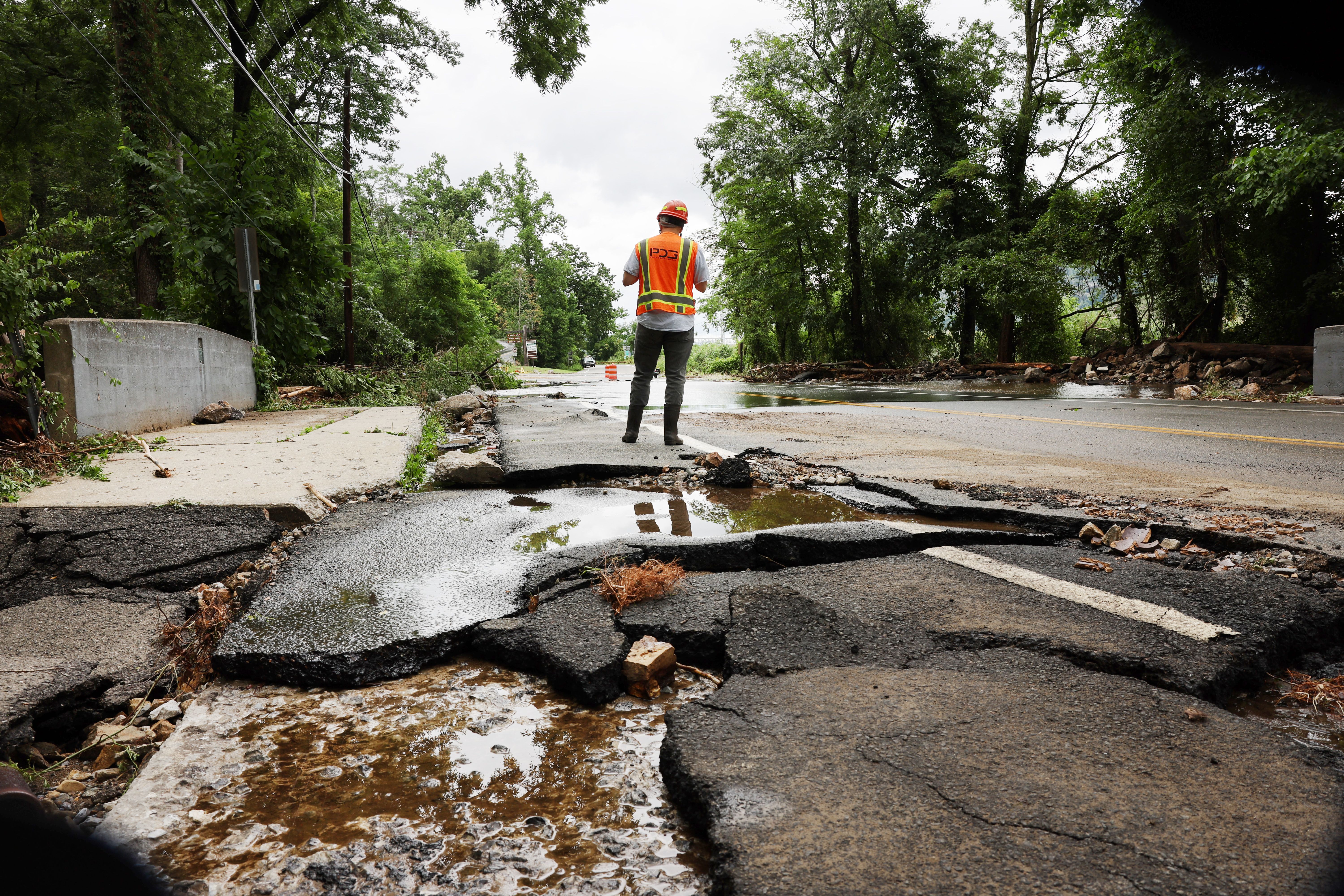 Workers survey a severely damaged road near Bear Mountain State Park following a night of heavy rain and flooding on July 10, 2023 in Highland Falls, New York. 