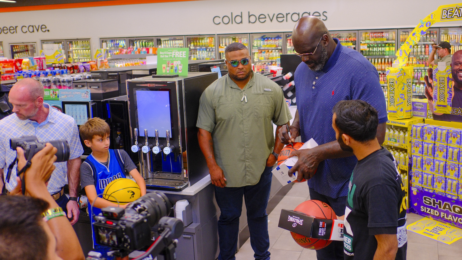 A tall basketball player signs a basketball while standing in a gas station