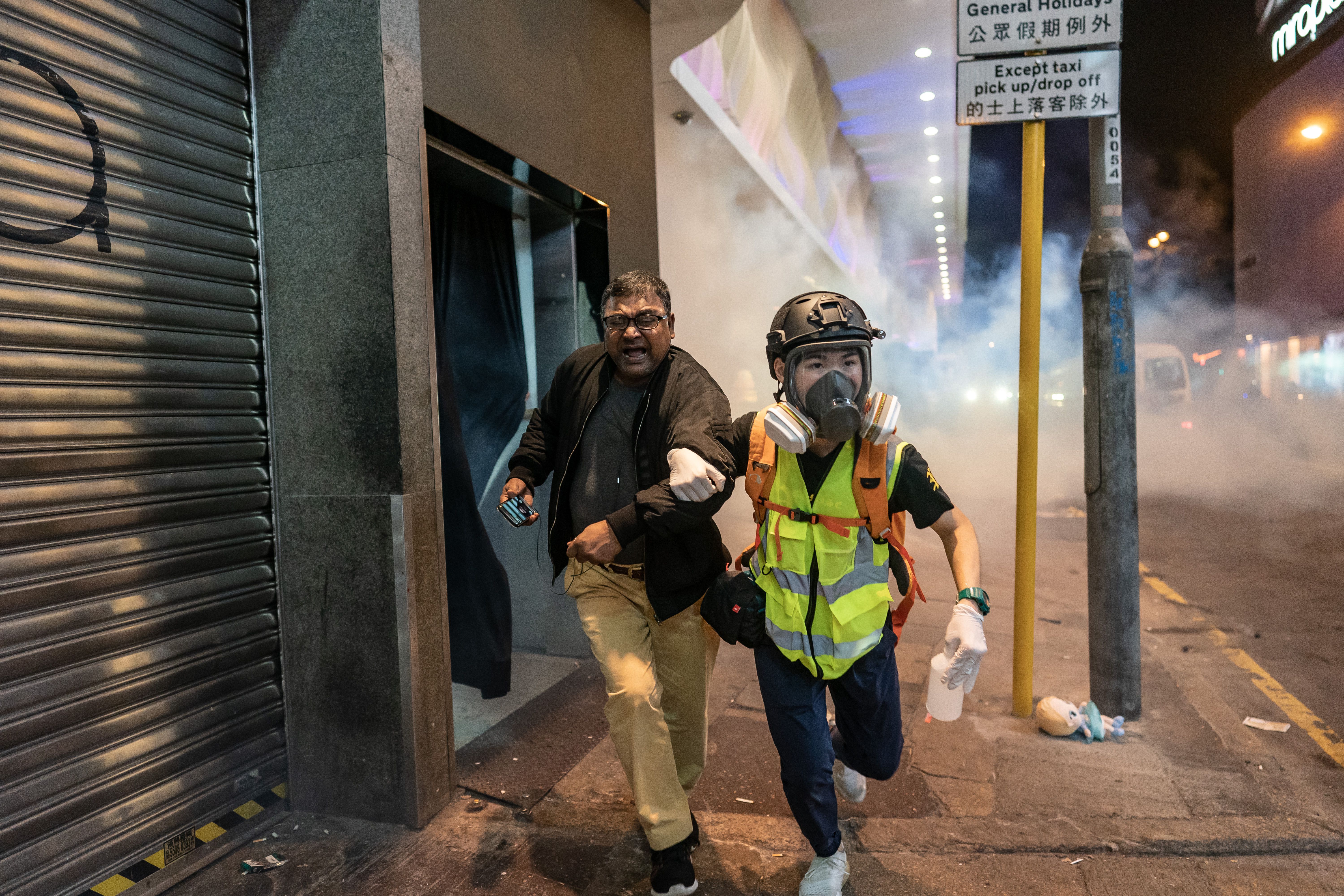 A volunteer medic assists a pedestrian after police fire teargas on the city's streets. 