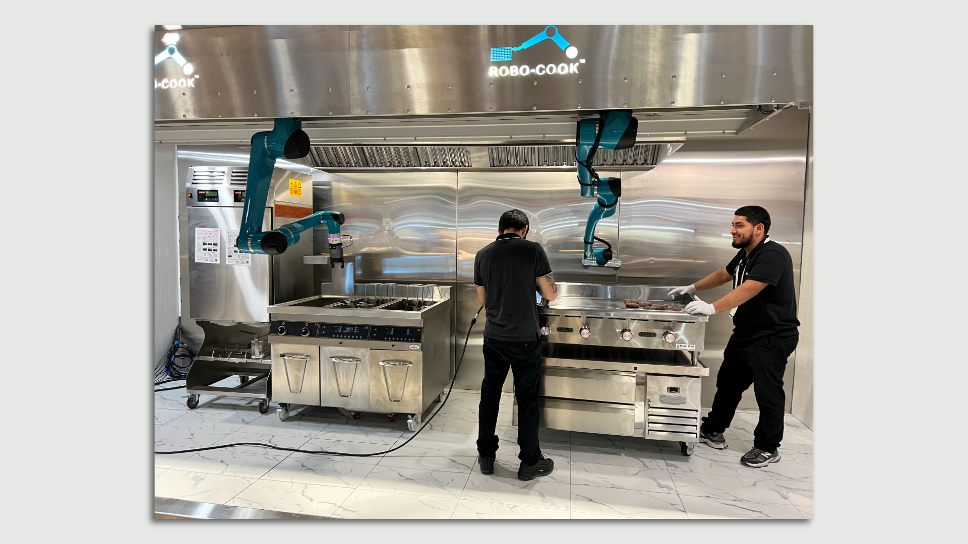 A large kitchen robotics system with two men standing around it.