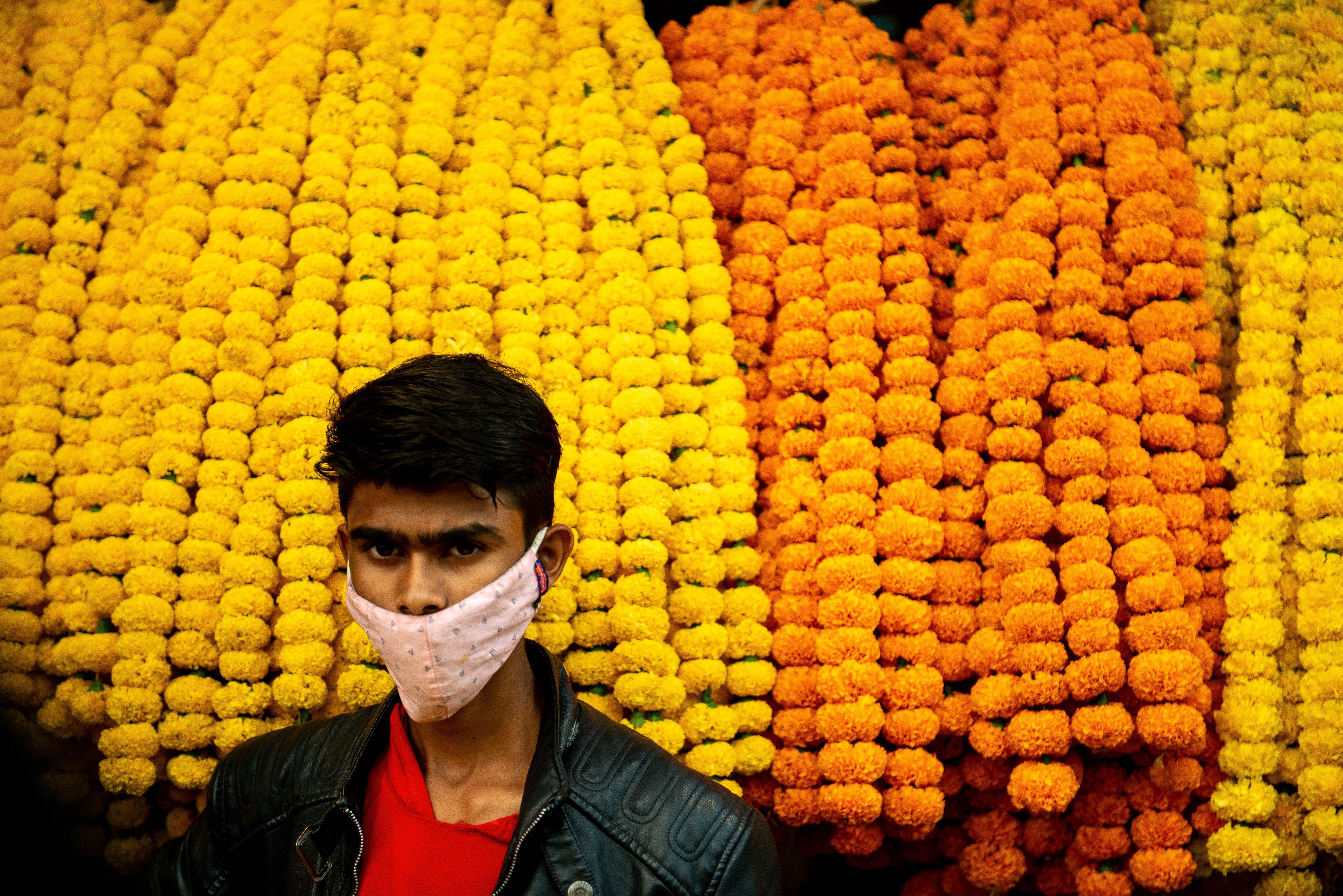  A man wearing a mask is seen infront of his marigold flower garlands display during Diwali in New Delhi. 