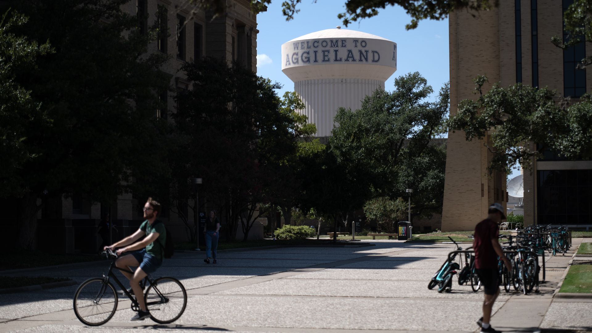 Photo of Texas A&M campus in College Station, Texas with a water tank saying "Welcome to Aggieland" and a student on a bike.