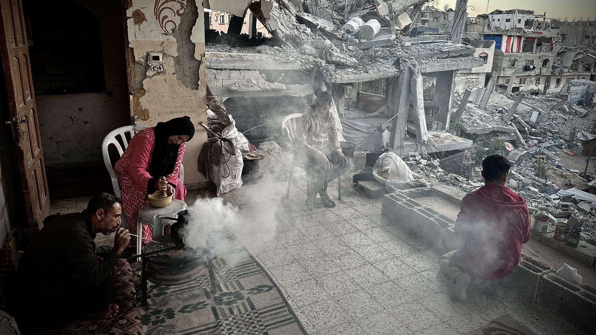 Palestinian Ellaham family, taking refuge in a damaged building, gather around a fire to keep themselves warm as they struggle with the cold weather conditions and food crisis in Khan Yunis, Gaza on December 4, 2024. 