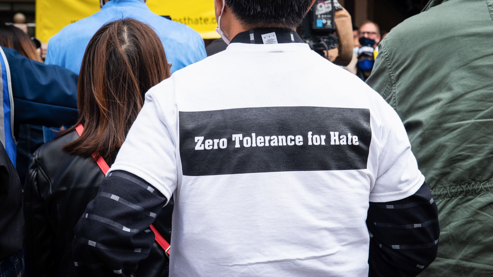 Photo of a protester wearing a shirt that says "Zero tolerance for hate" on the back