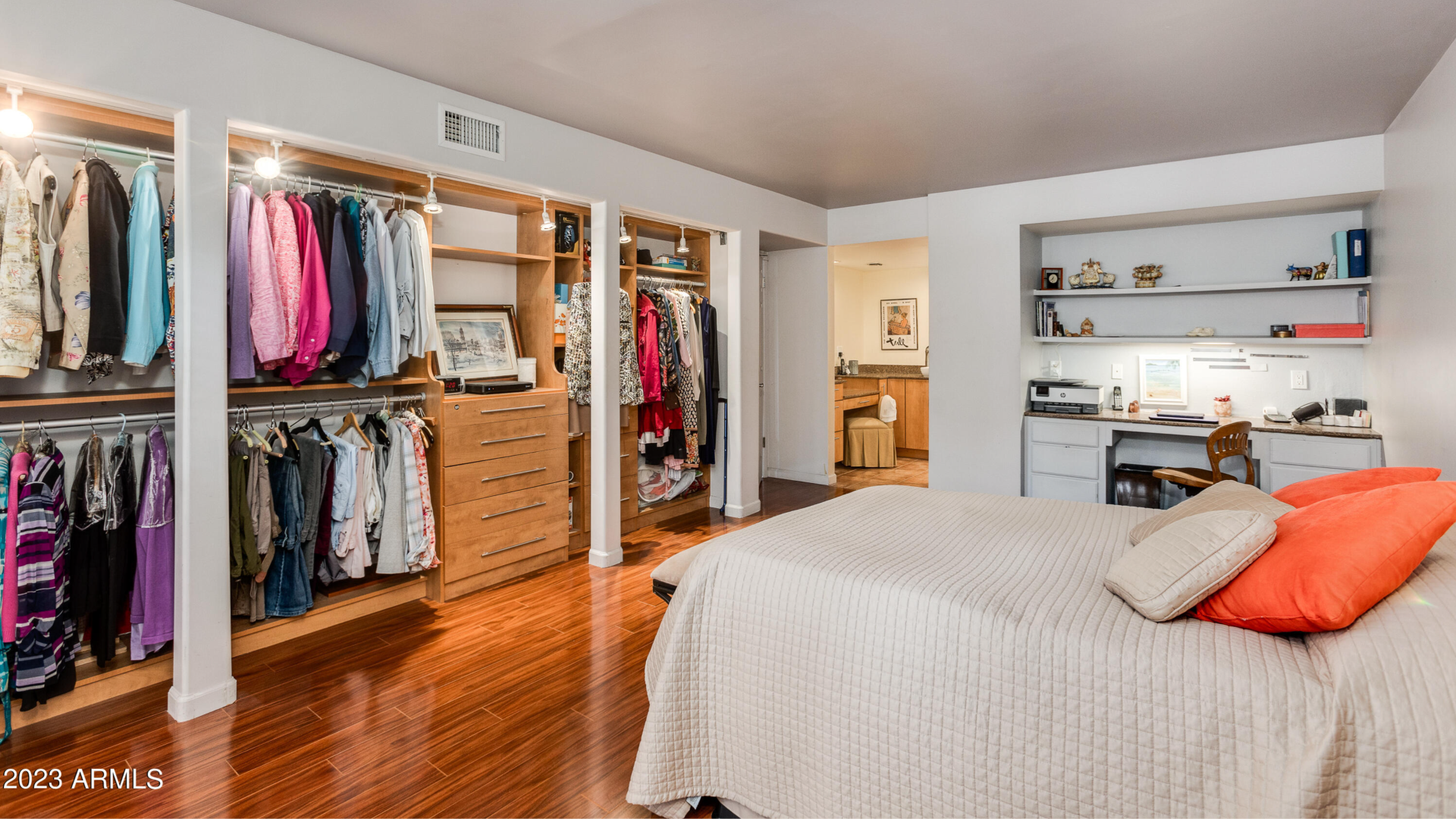 A bedroom with a built-in desk and exposed closet. 