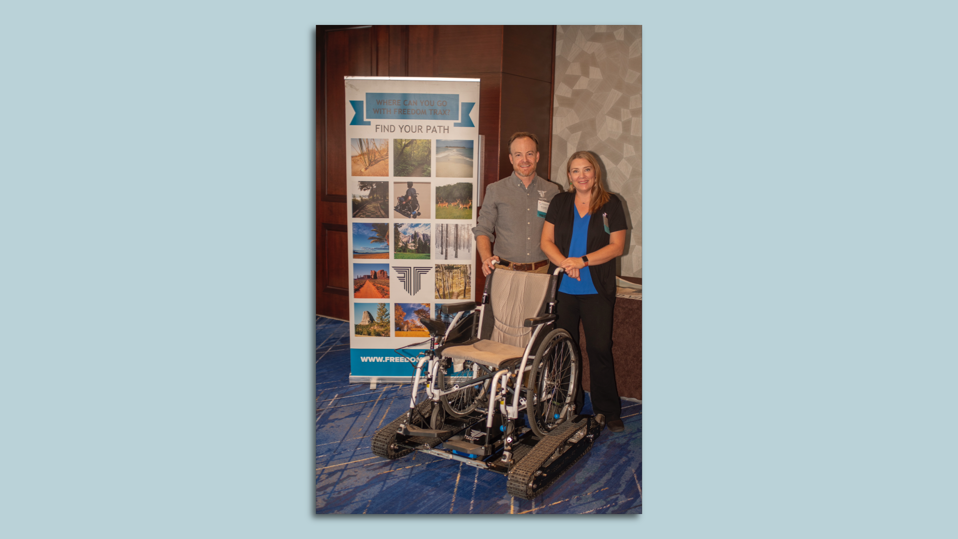 A man and woman stand next to a wheelchair with an attachment. 