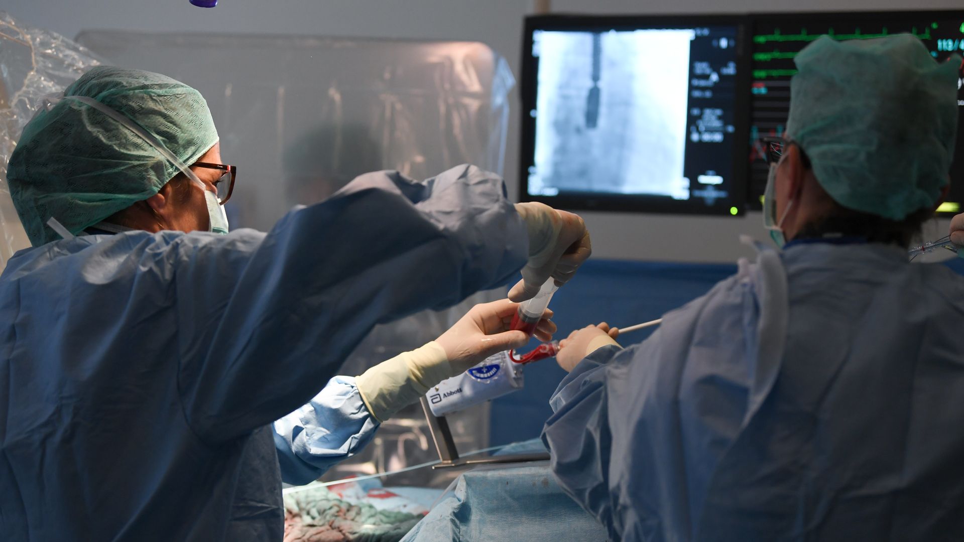 Surgeons prepare an operating room for a patient.