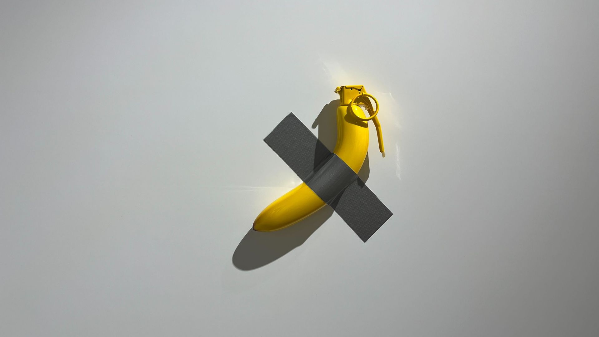 A banana with duct tape on a wall. 
