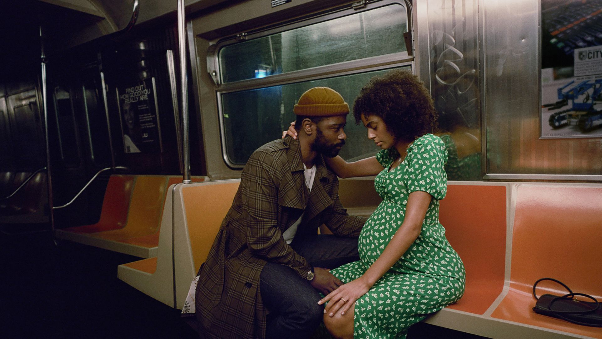A photo showing a scene from "The Changeling." A man wearing a beanie and a long coat is sitting with a woman who is pregnant on an empty subway. His hand is on her leg and he's staring at her while she's looking down.